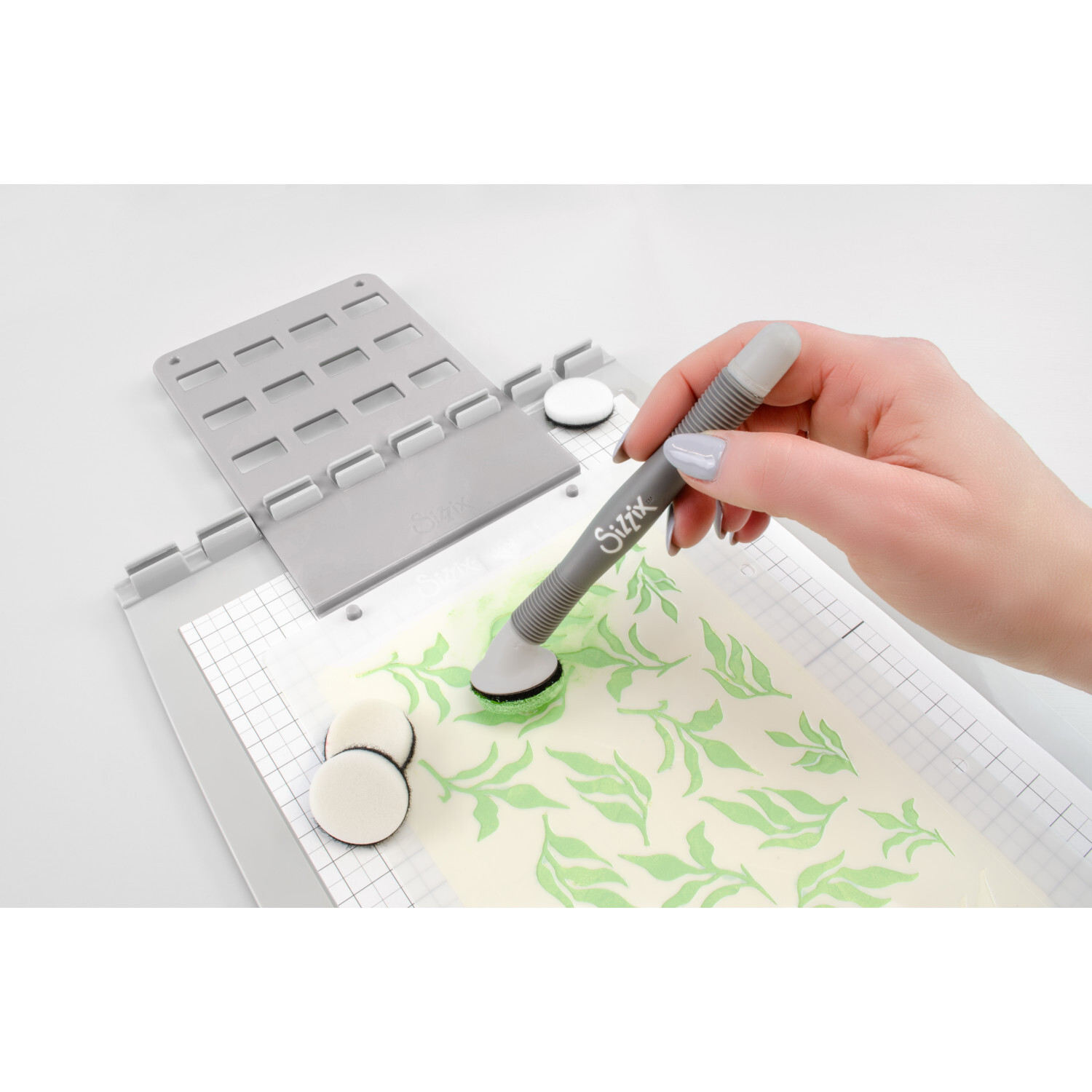 Studio Blending Tool Set Grey: Hand nutzt graues Sizzix-Werkzeug zum Schablonieren auf Papier.