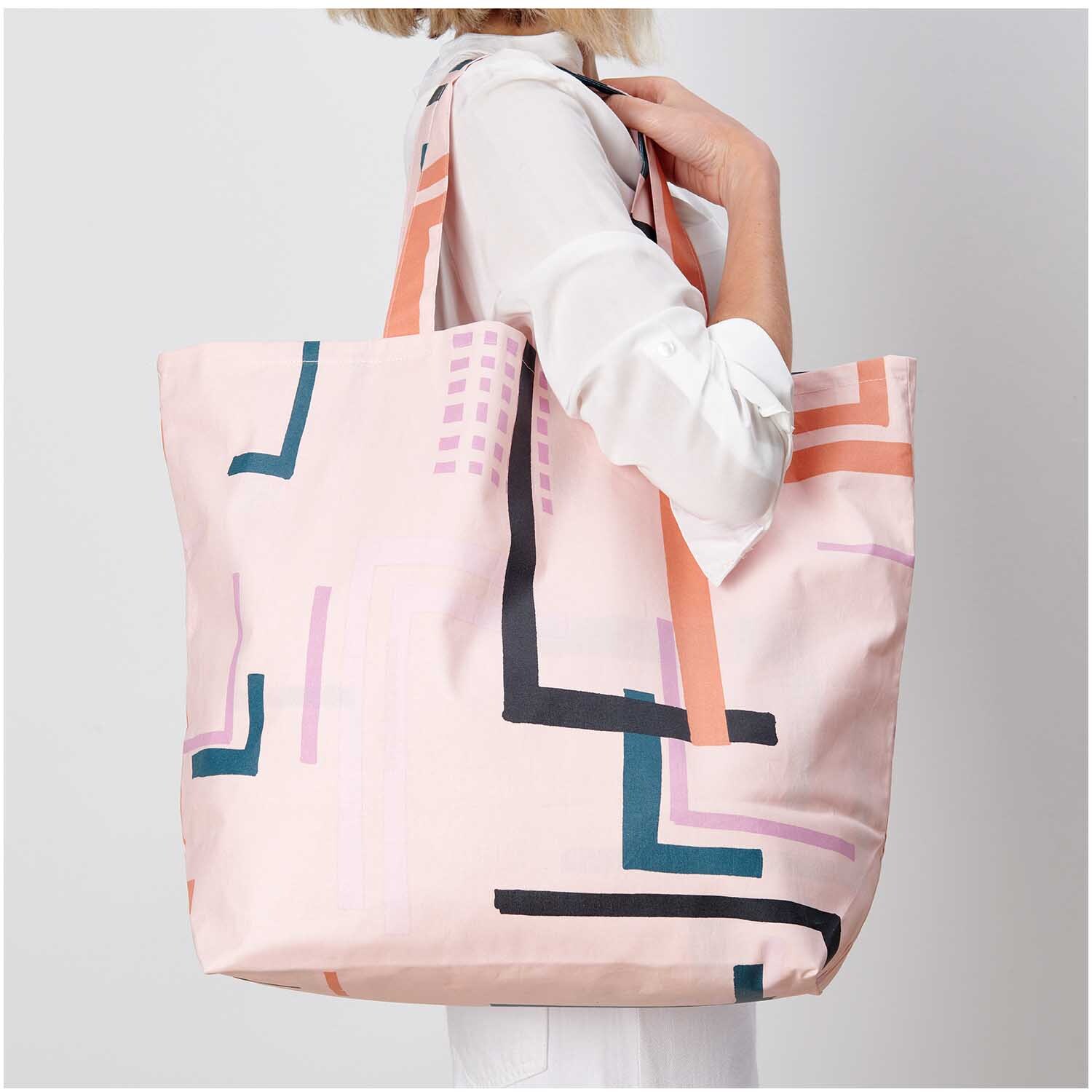 Shopper Okina Hana rosa 41x55x19cm mit geometrischem Muster, getragen von Frau in weißem Hemd.