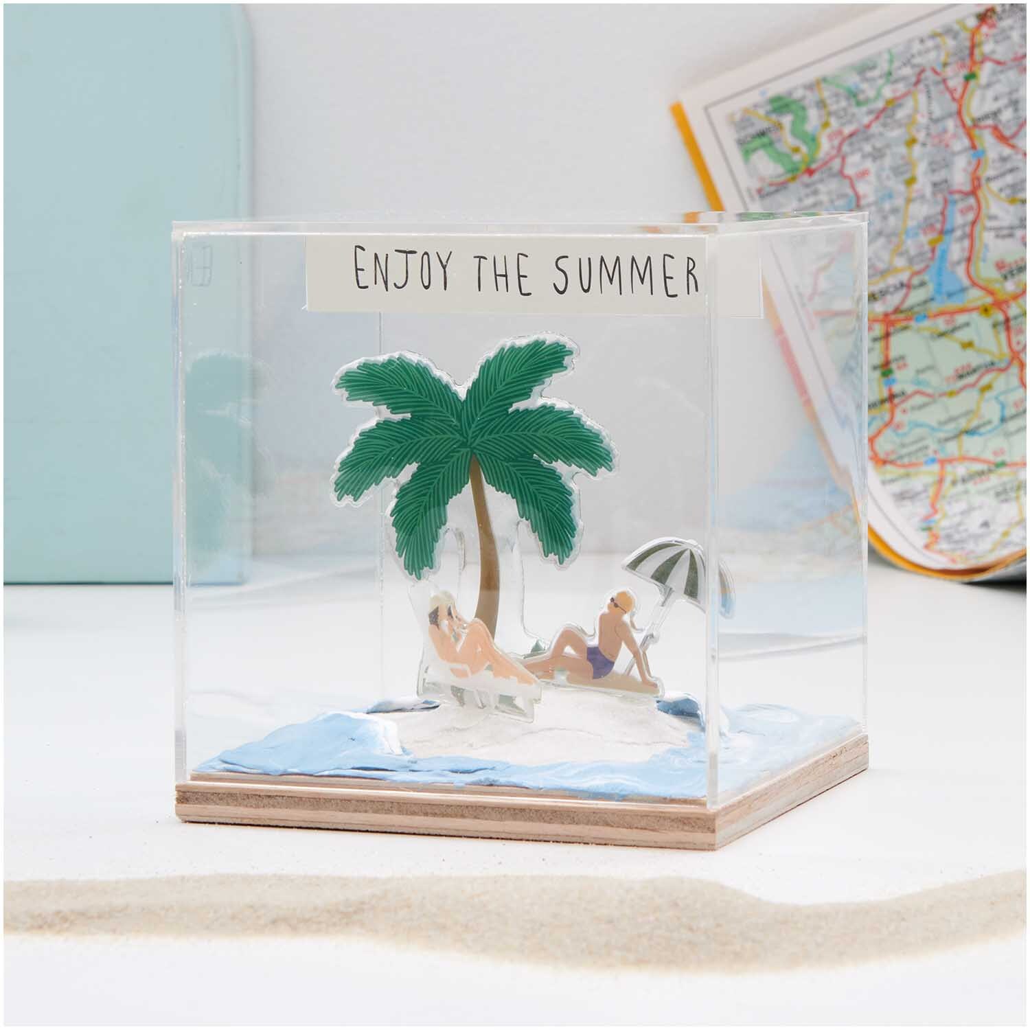 Figurico Modelliermasse Sand 105g: Miniatur-Strandszene mit Palme und Figuren in einem transparenten Würfel.
