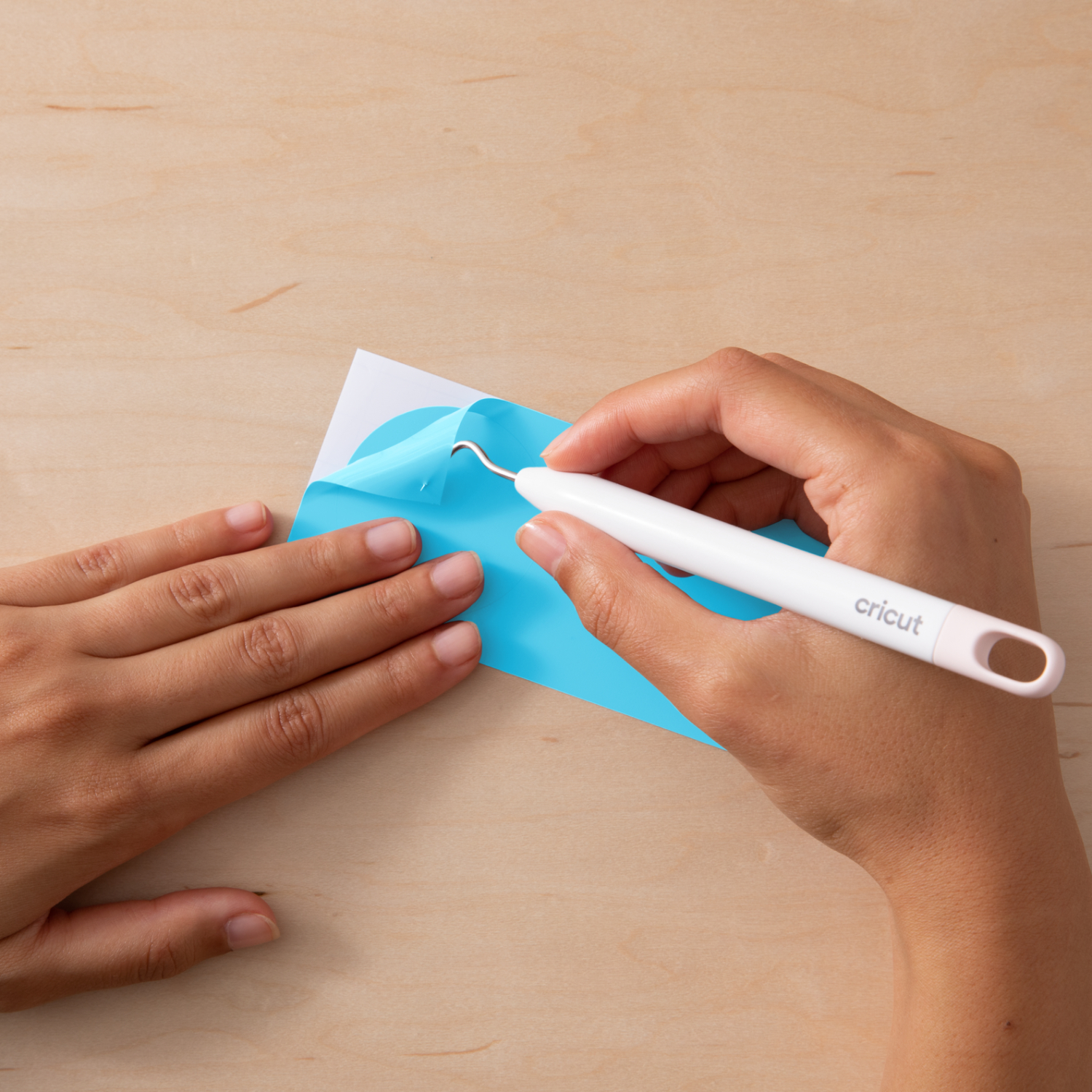 Color change Vinyl HOT Permanent: Eine Hand nutzt ein Cricut-Werkzeug, um blaues Vinyl auf Holz zu bearbeiten.