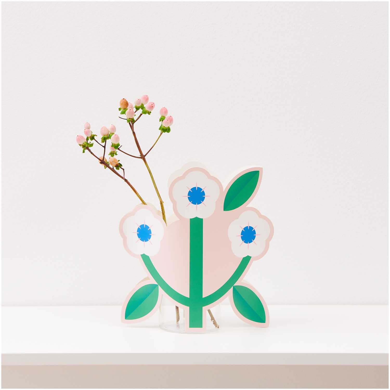 Paper Poetry Vasencover Blume 21x20cm von Rico Design zeigt ein florales Design mit grünen Blättern und weißen Blüten auf einem Tisch.