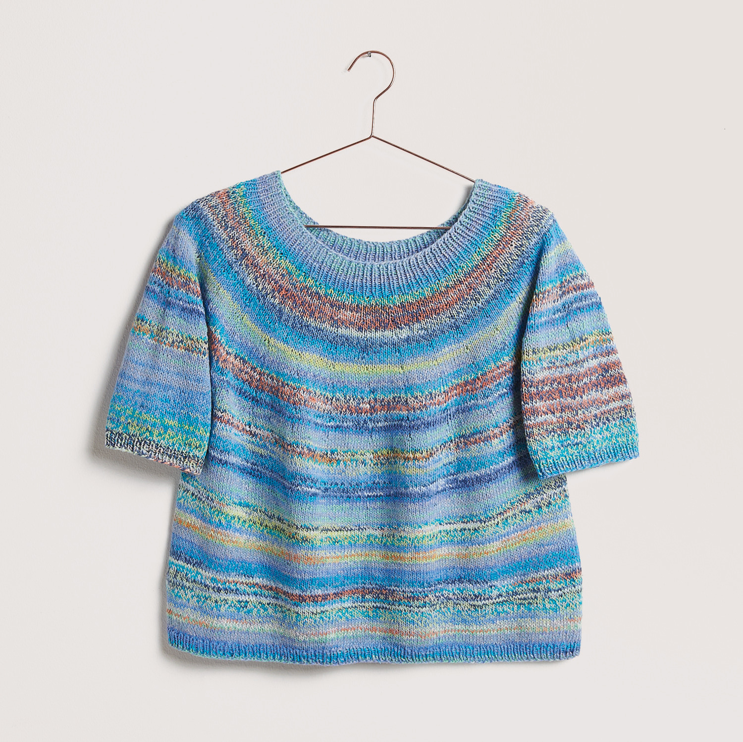 Blaues Shirt auf grauem Hintergrund – zum Strickset