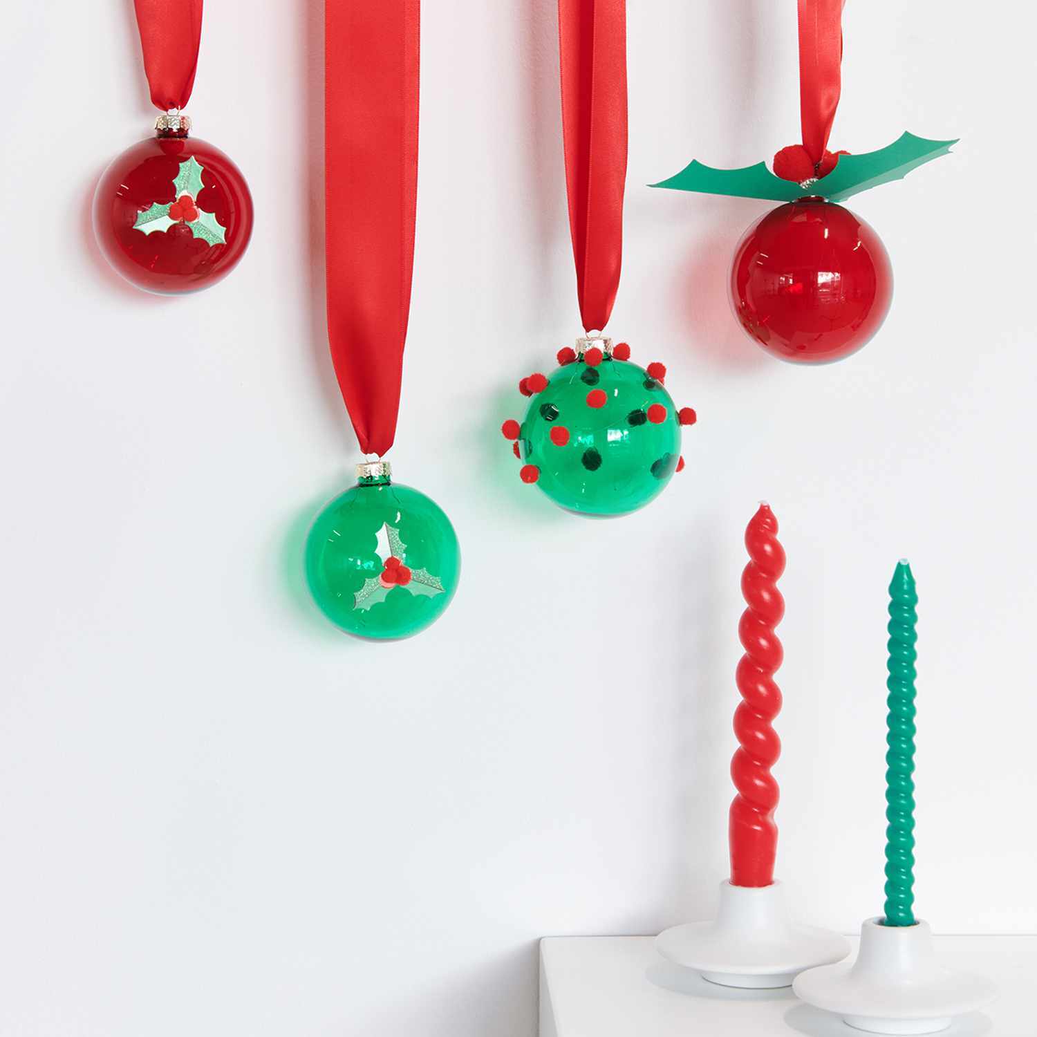 Bastelanleitung Baumschmuck in klassischen Farben: Rote und grüne Kugeln mit Bändern und Kerzen.