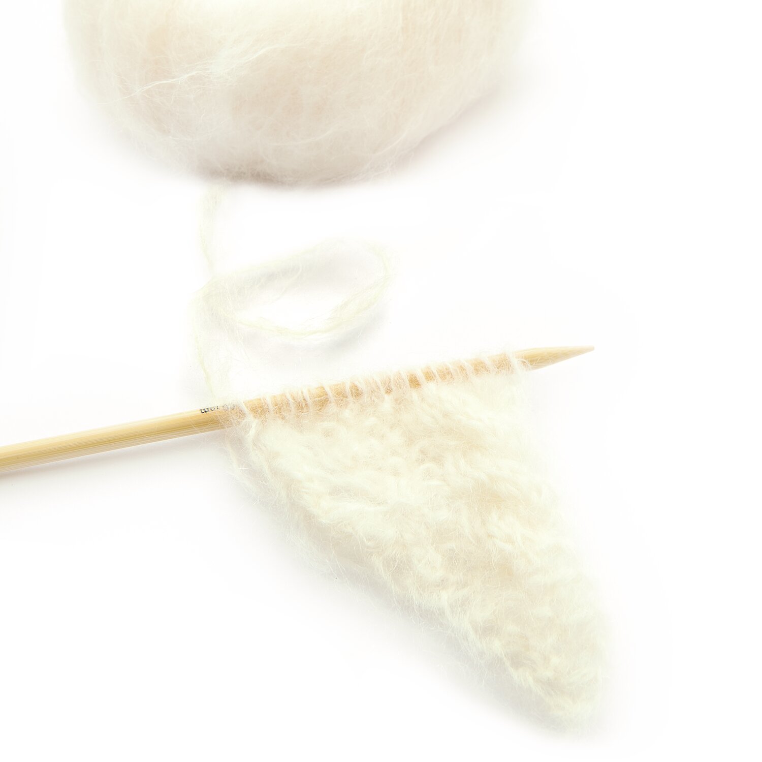 Fashion Mohair Merino Chunky von Rico Design: Cremefarbenes Garn mit Stricknadel und gestricktem Muster. Ideal für warme, weiche Projekte.