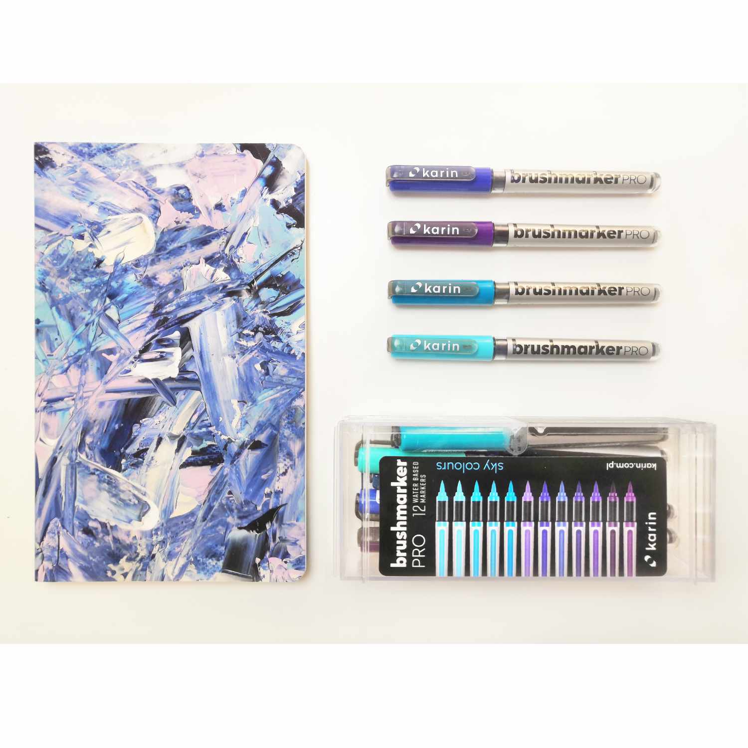 Brushmarker PRO Sky Colours Set mit 12 Farben von karin, neben einem abstrakten Notizbuch. Ideal für kreative Projekte.
