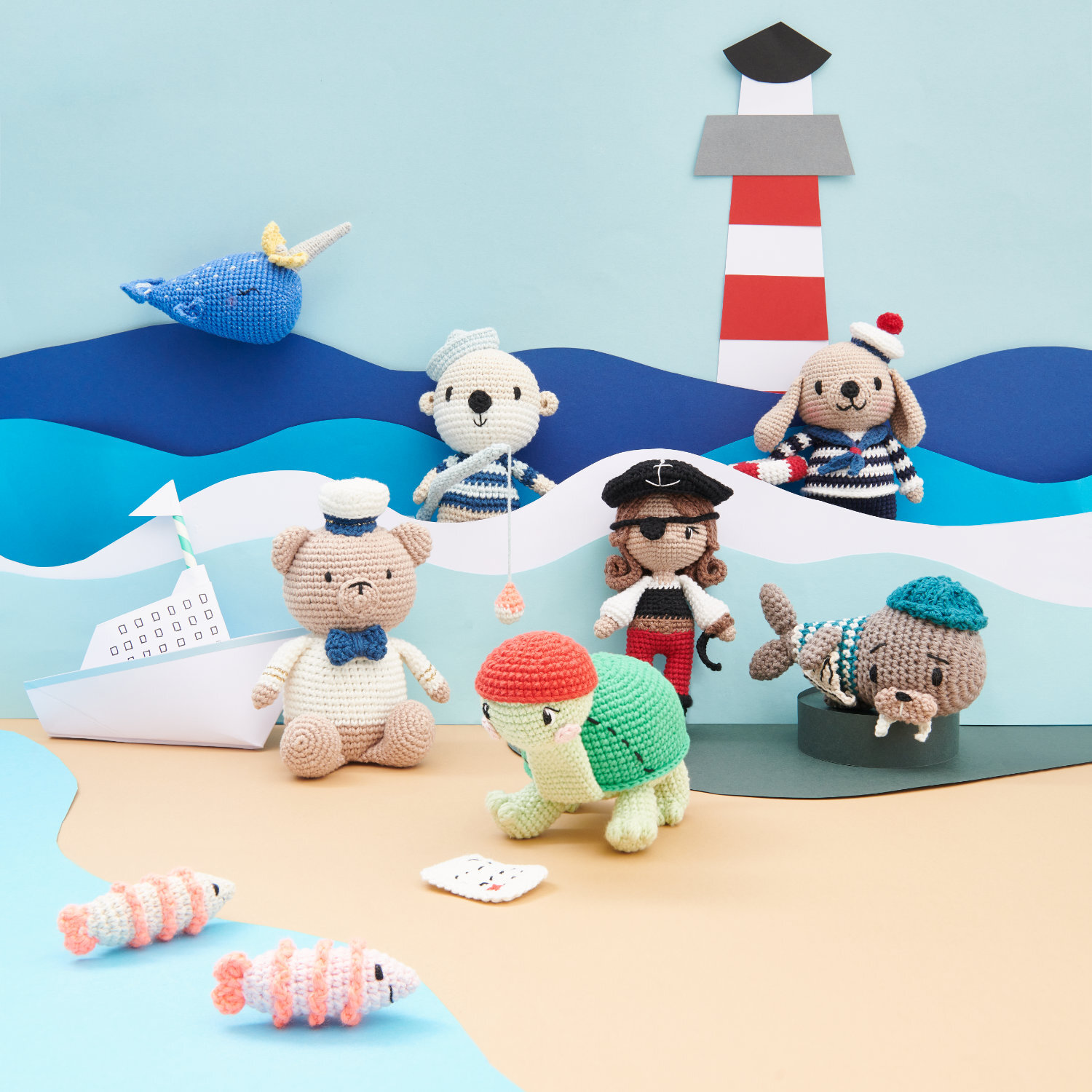 Creative Ricorumi dk Spring CAL Box 1 Maritime: Häkelfiguren am Strand mit Leuchtturm im Hintergrund, von Rico Design.