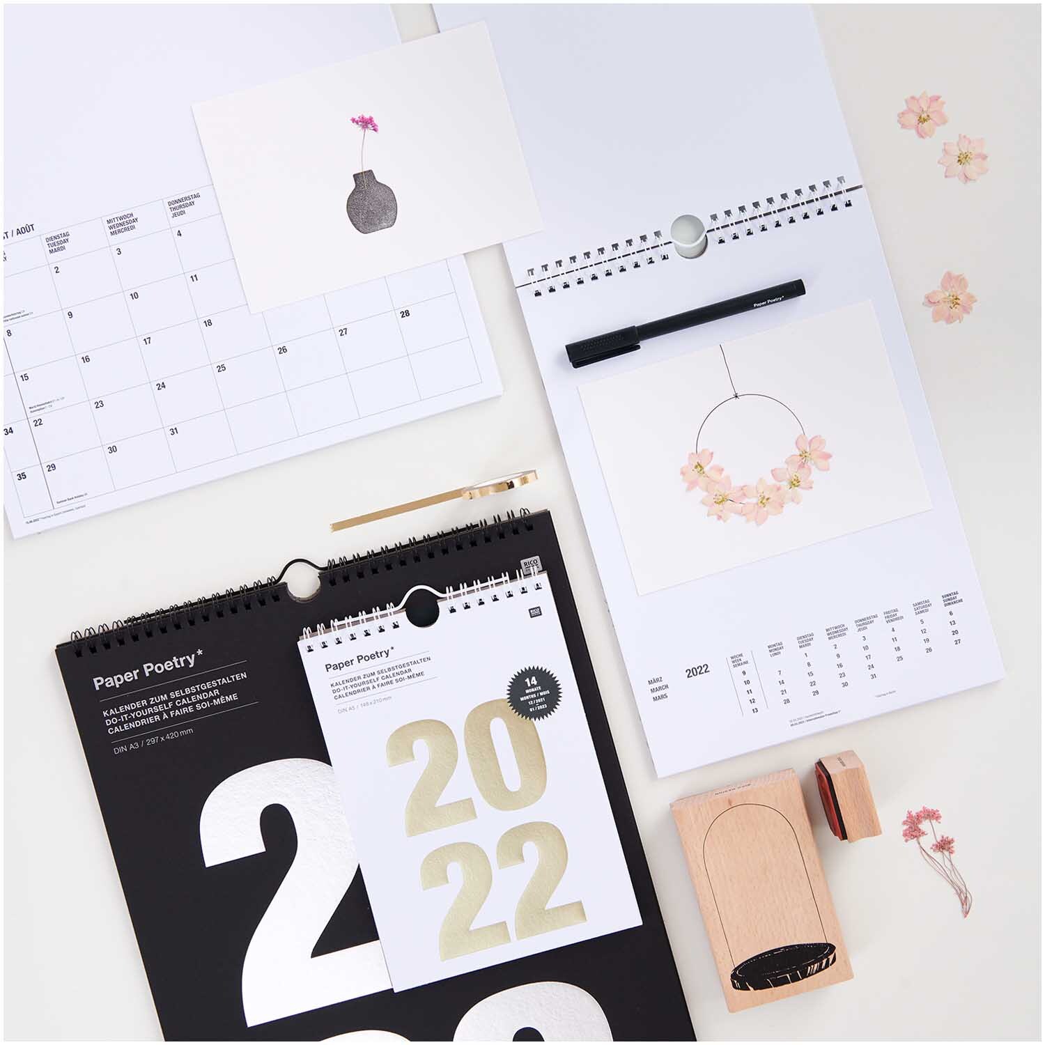 Gepresste Blüten Rittersporn rosa 8 Stück von Rico Design auf einem Schreibtisch mit Kalendern und Stempel.