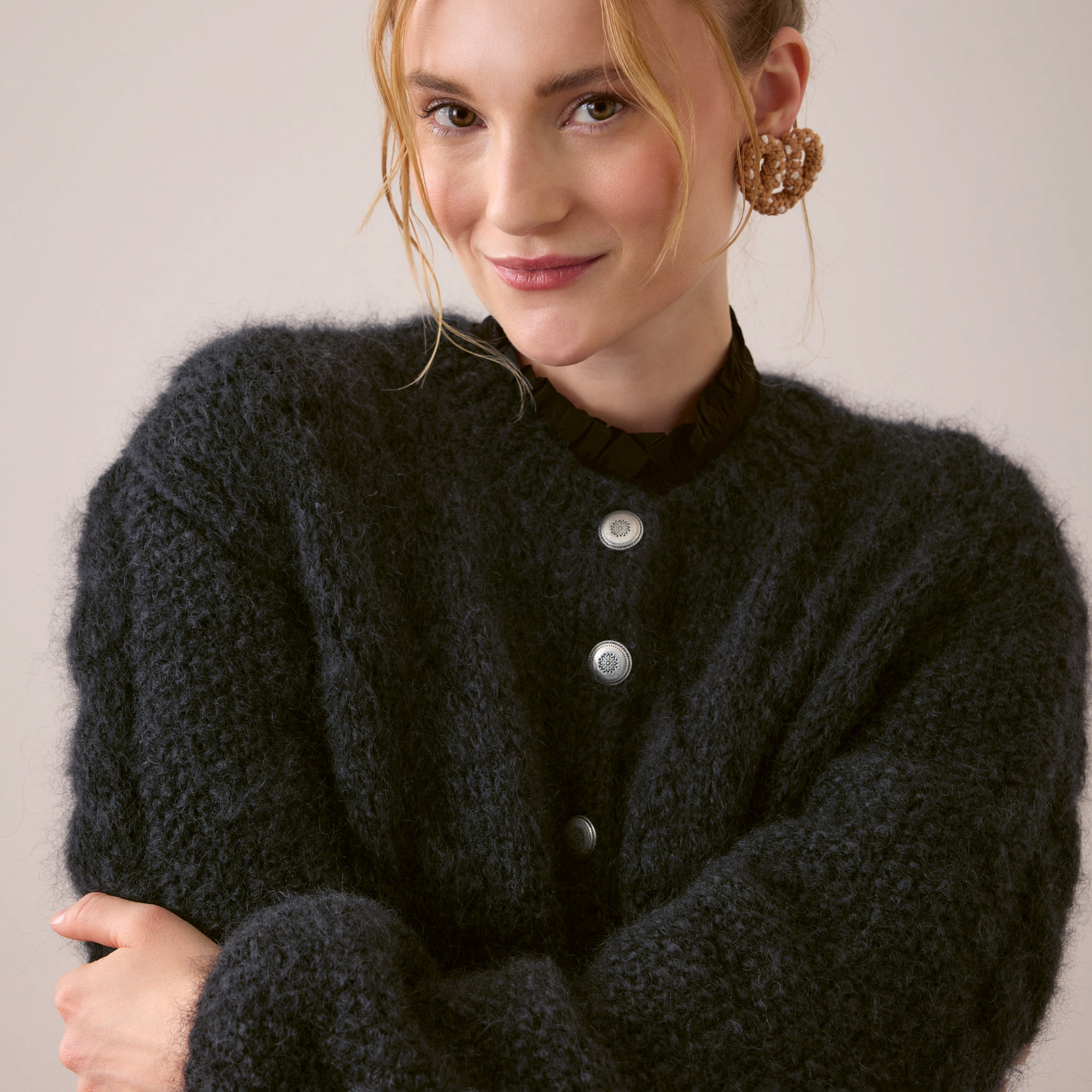 Fashion Mohair Merino Chunky: Frau trägt schwarze Strickjacke mit silbernen Trachtenknöpfen, elegant kombiniert.