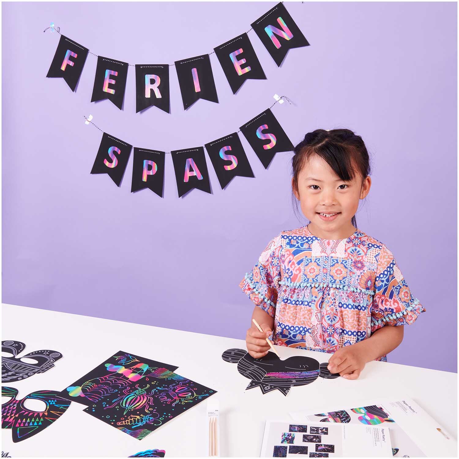 Paper Poetry Kratzpapier Masken Set mit Kind am Tisch, das eine Maske gestaltet. Hintergrund in Lila.