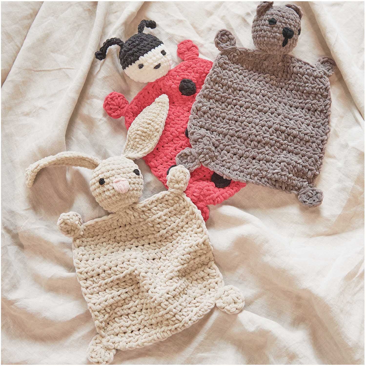 Creative Chenillove: Drei gehäkelte Kuscheltiere auf einem Tuch, darunter ein Hase, ein Marienkäfer und ein Bär.