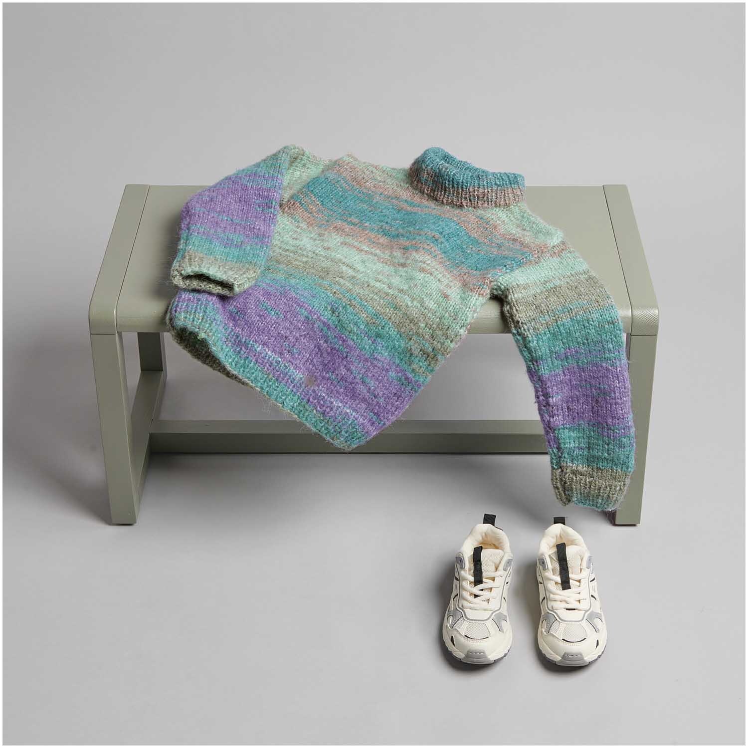 Strickset Pullover Modell 11 aus Kids Nr. 12 auf grauer Bank, daneben weiße Turnschuhe.