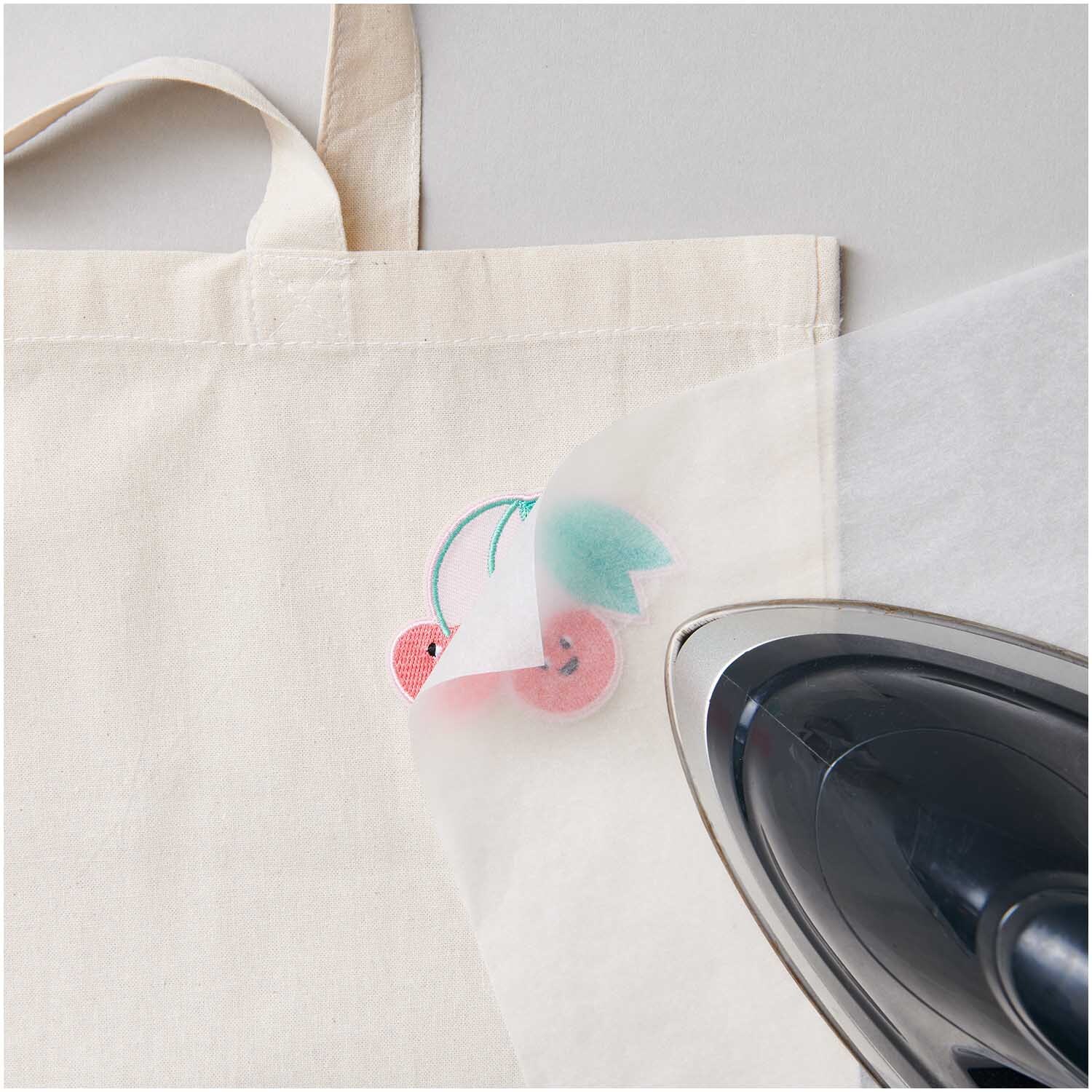 Patch Doppelkirsche zum Aufbügeln auf einer Stofftasche mit Bügeleisen, ideal für kreative Designs.