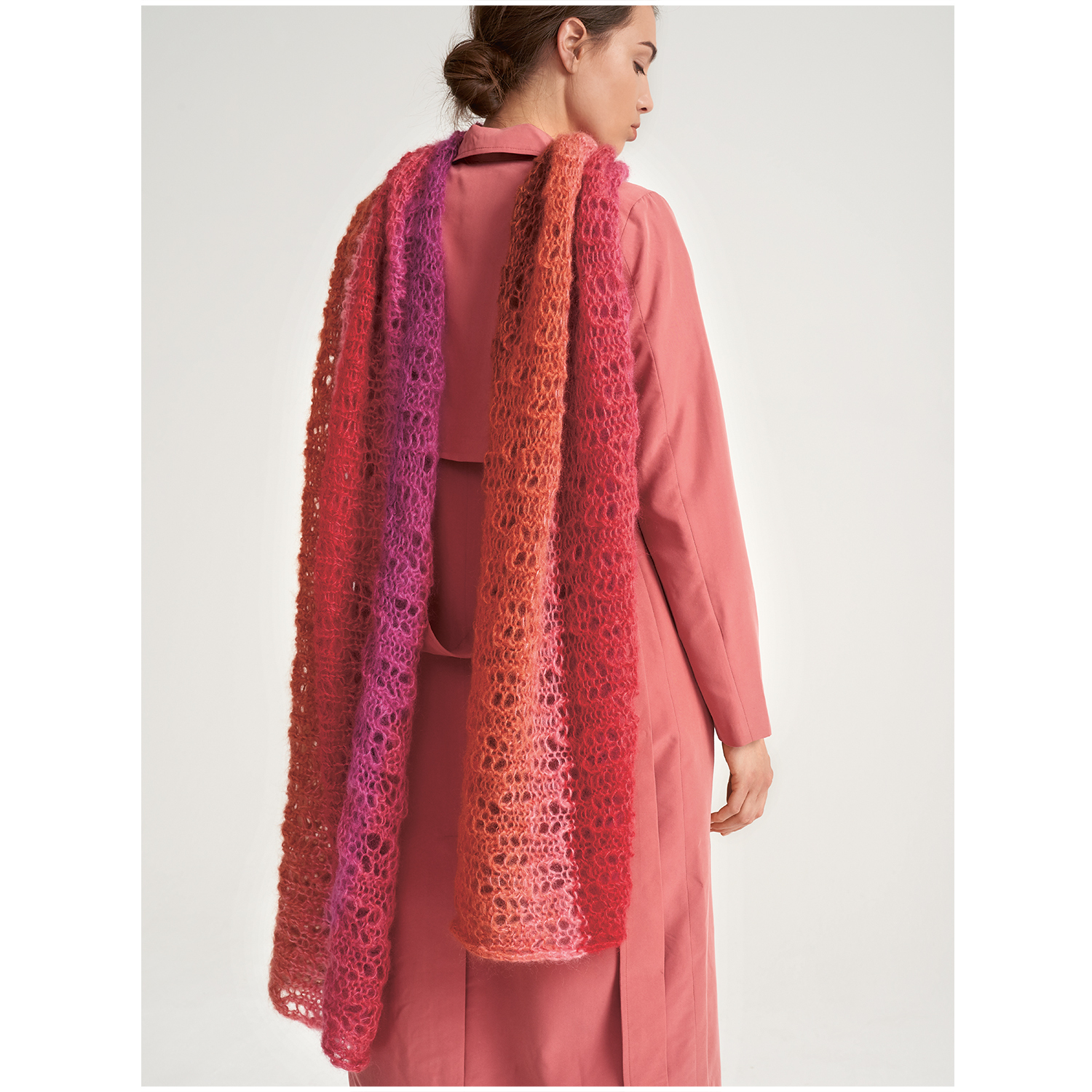 Essentials Super Kid Mohair Loves Silk Colourlove: Frau trägt langen, gehäkelten Schal in Rot- und Rosatönen von Rico Design.