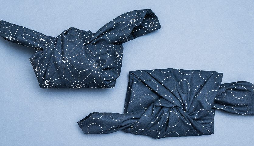 Anleitung Furoshiki: Ein Geschenk in buntem Stoff kunstvoll verpackt, inspiriert von japanischer Tradition.
