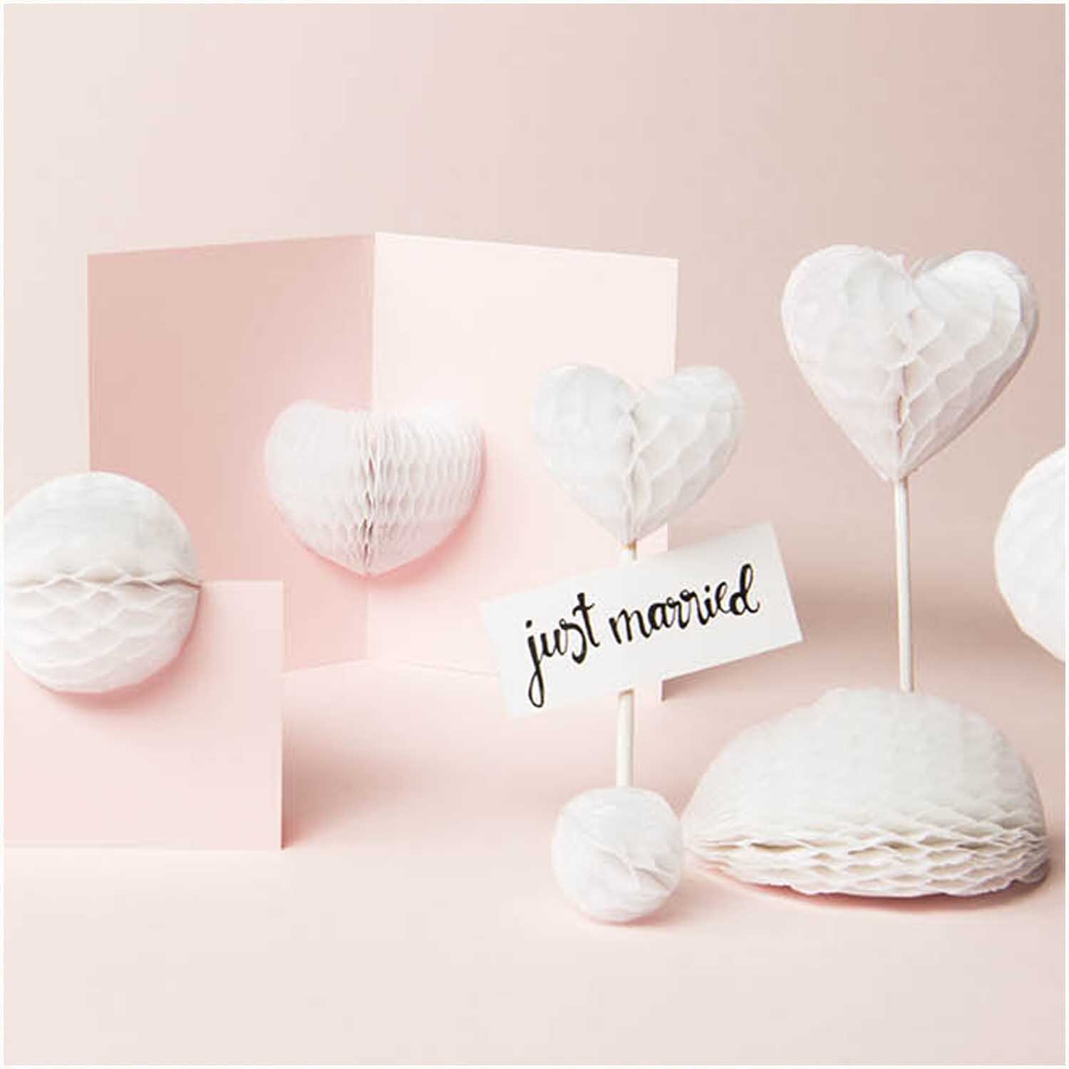 Wabenpapier weiß 20x33cm 4 Bogen von Rico Design, geformt als Herzen und Kugeln, mit "just married"-Schild auf rosa Hintergrund.