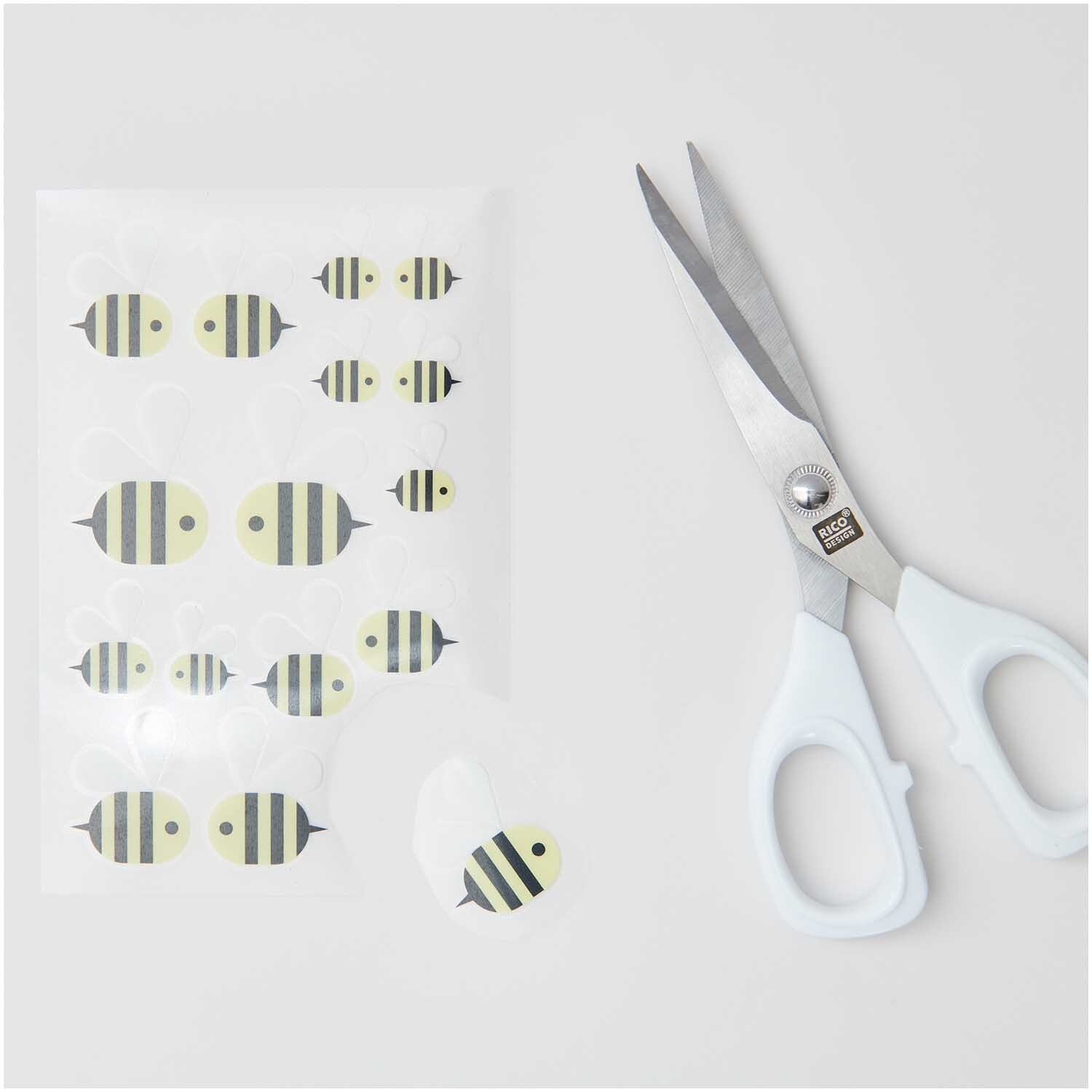 Transfermotiv Biene: 15 gelb-schwarze Bienenmotive von Rico Design neben einer weißen Schere auf grauem Hintergrund.