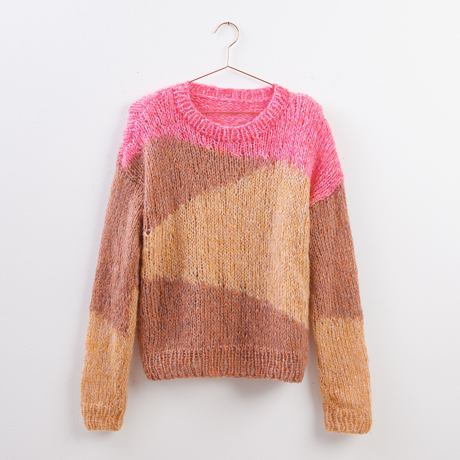 Strickanleitung Pullover mit geometrischem Muster in Rosa, Braun und Beige auf einem Kleiderbügel.