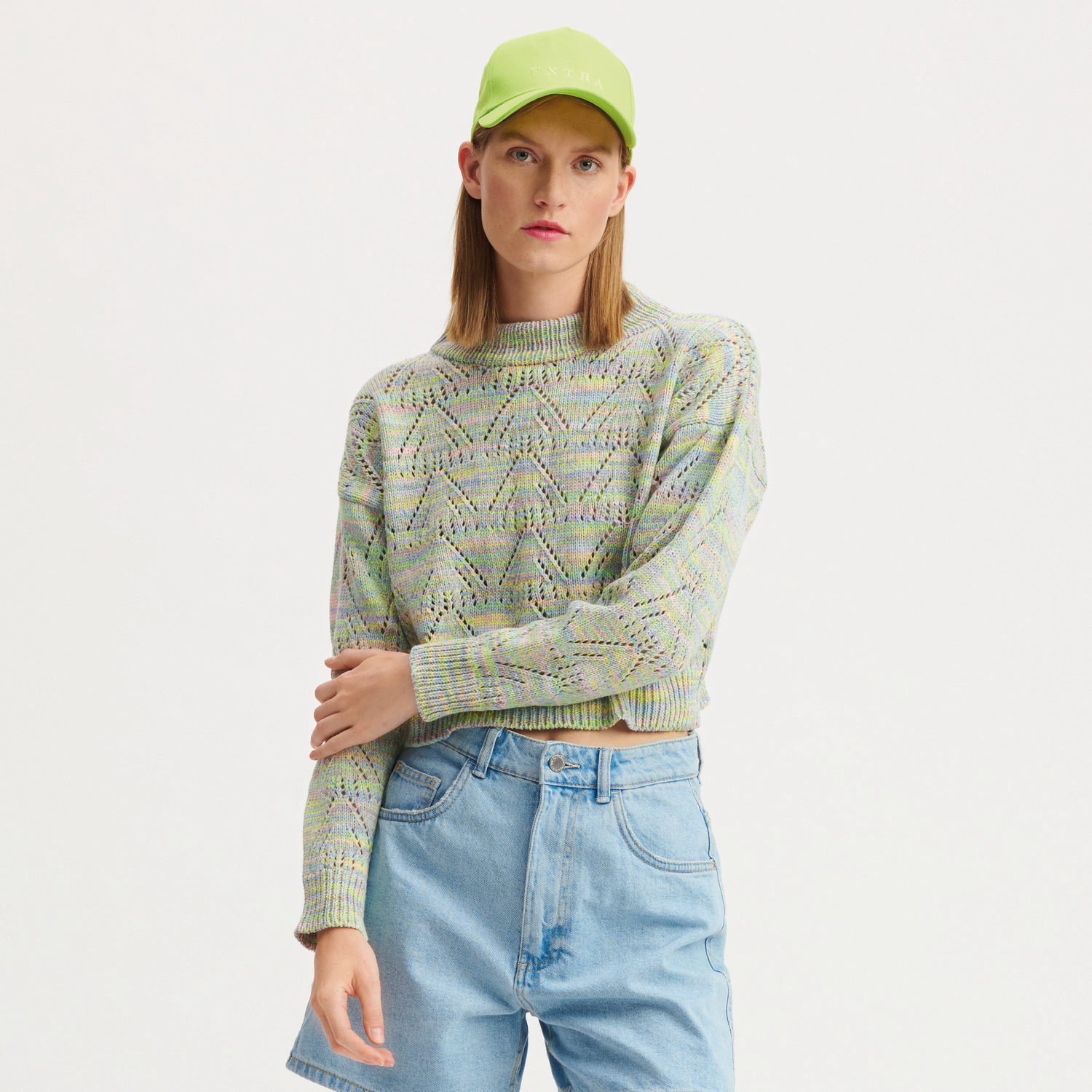 Creative Summer Sprinkles Strickset Pullover Modell 38 in Pastelltönen, getragen von Frau mit grüner Kappe und blauen Jeans.