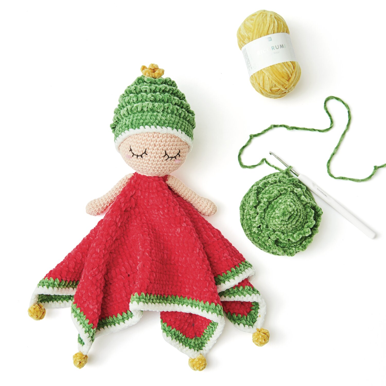 Ricorumi Baby Blankies Nilli Nilli: Gehäkelte Puppe mit rotem Umhang, grünem Hut und Garn in verschiedenen Farben.