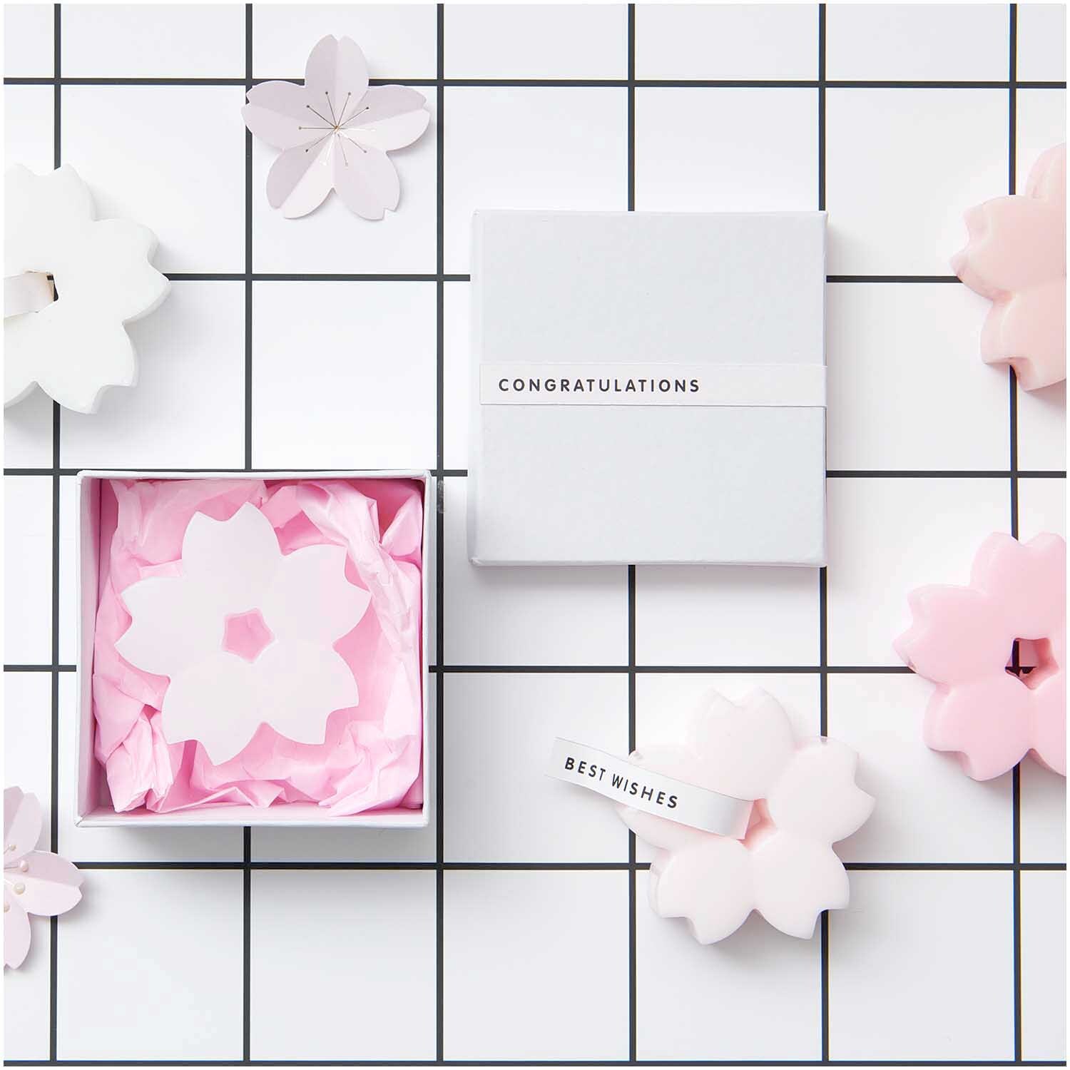 Seidenpapier 50x70cm 5 Bogen von Rico Design in einer Geschenkbox mit rosa Blüten auf kariertem Hintergrund.