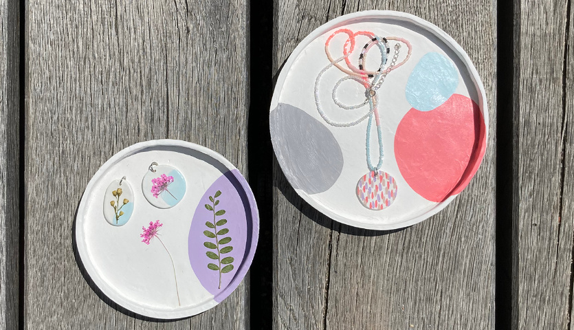 Bastelanleitung Schmuckschalen und Kettenanhänger aus Modelliermasse auf Holzoberfläche mit floralen und abstrakten Designs.