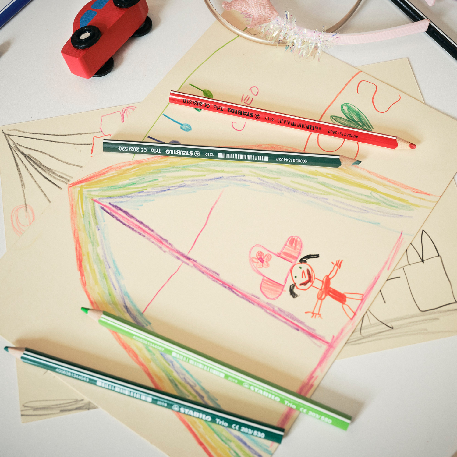 STABILO Trio Dick Buntstifte: Bunte Stifte auf Zeichnungen mit Regenbogen und Kindermotiven, 12 Stück.
