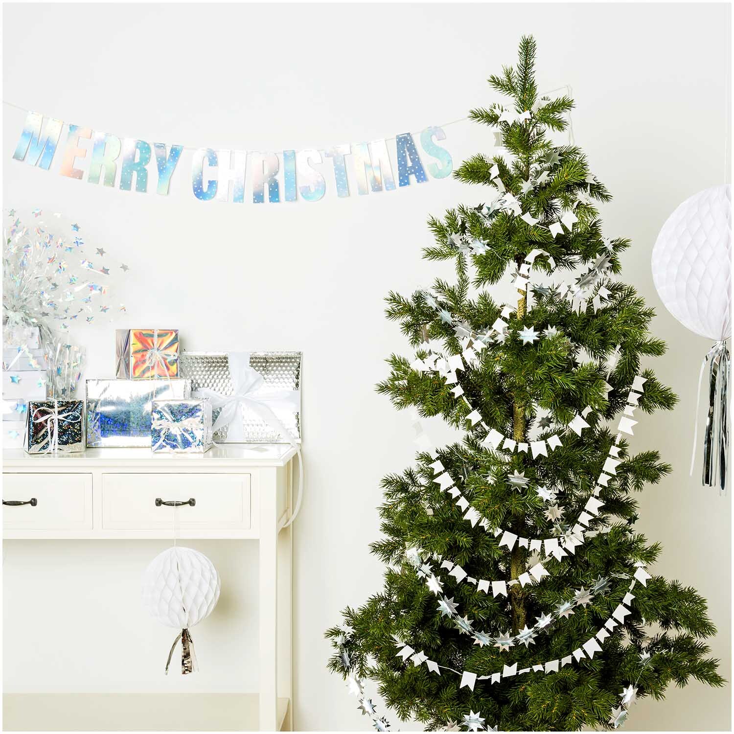 Paper Poetry Girlande Wimpel dekoriert einen Weihnachtsbaum mit weißen Papierwimpeln, umgeben von festlicher Dekoration.
