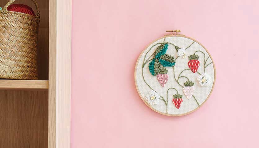 Anleitung Punch Needle Bild mit Erdbeeren gestalten: Wanddekoration mit Erdbeermotiv auf rosa Hintergrund.