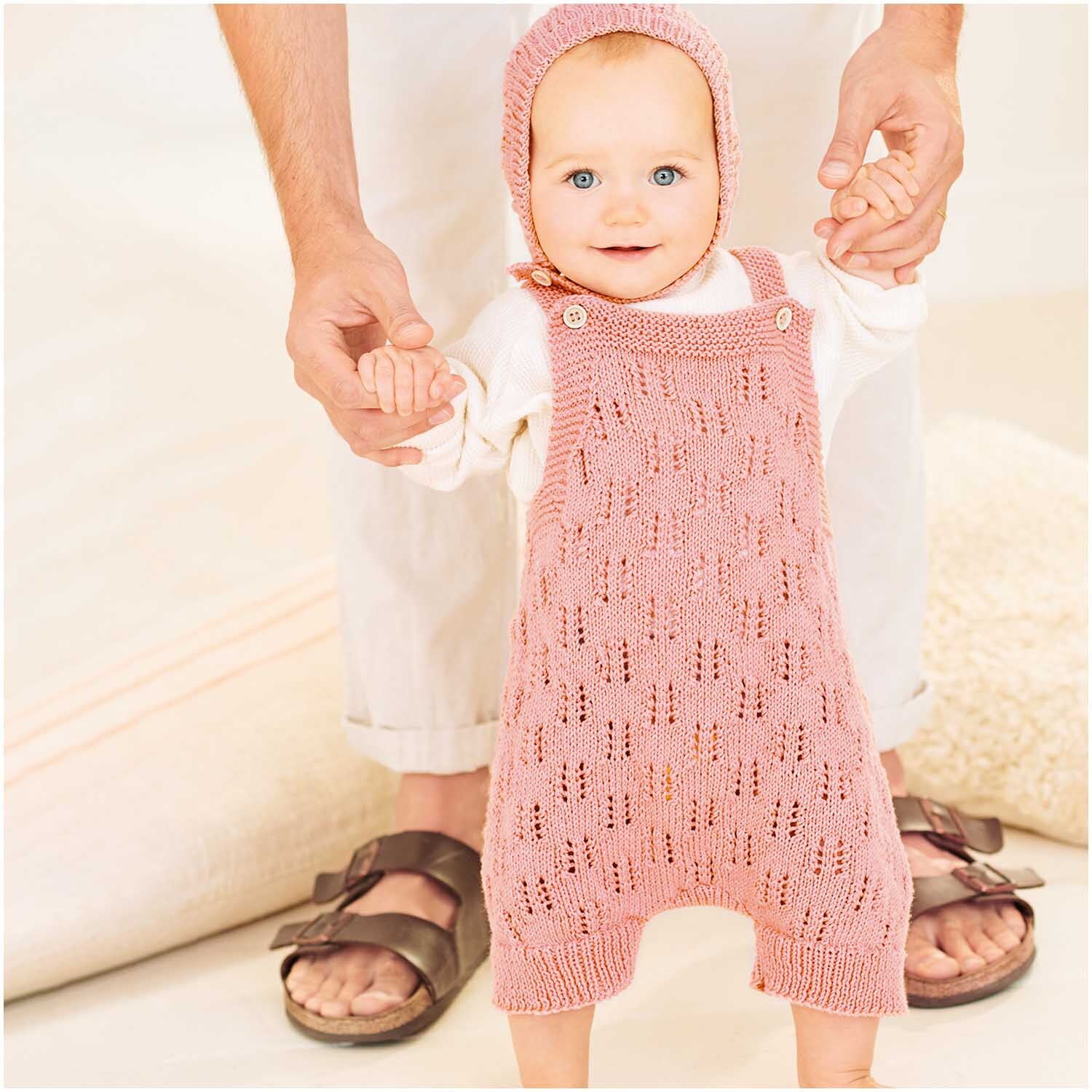 Baby Organic Cotton: Ein Baby trägt einen gestrickten altrosa Strampler aus Bio-Baumwolle.
