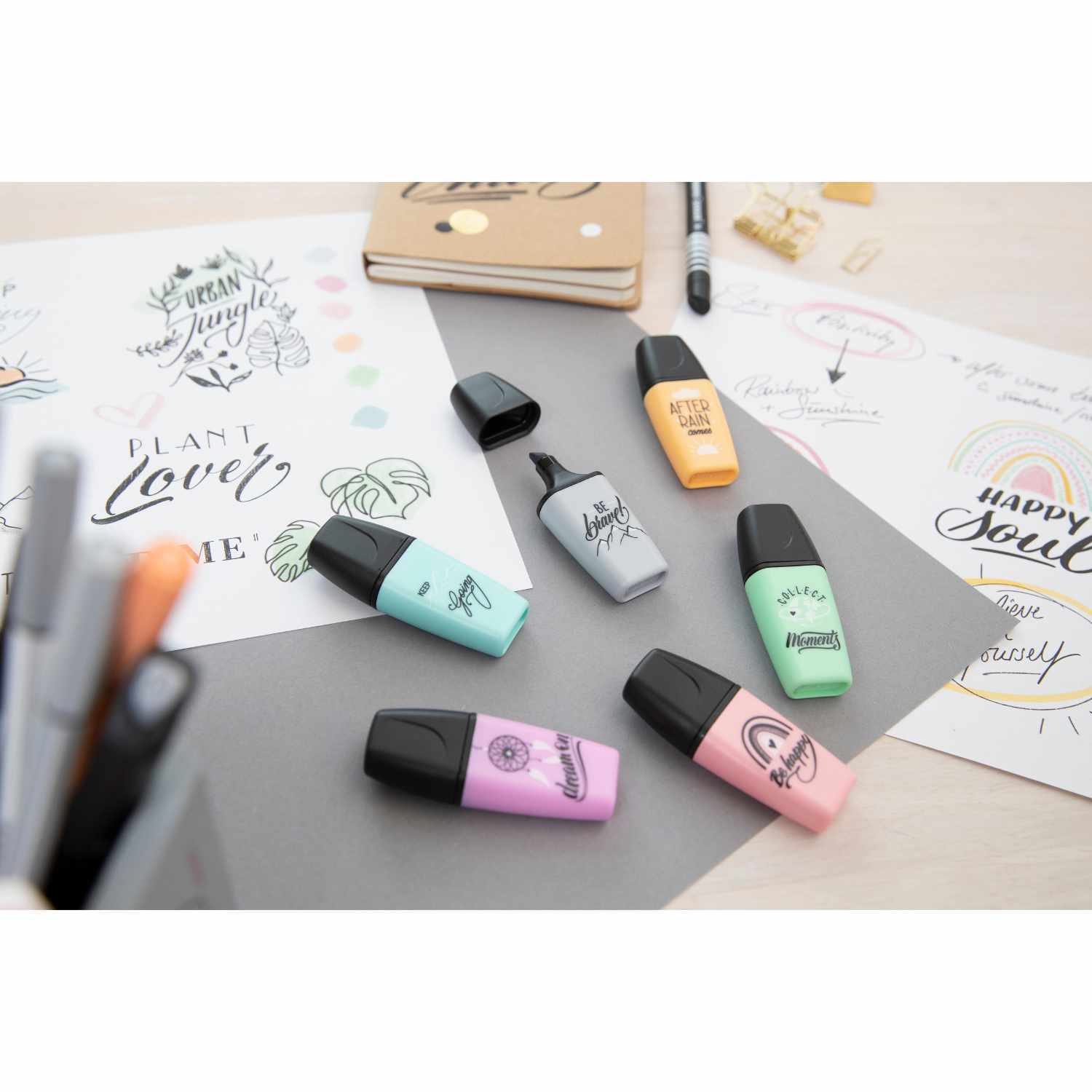 Textmarker Boss Mini Pastelllove Edition in verschiedenen Farben auf einem Schreibtisch mit kreativen Zeichnungen und Notizbuch.
