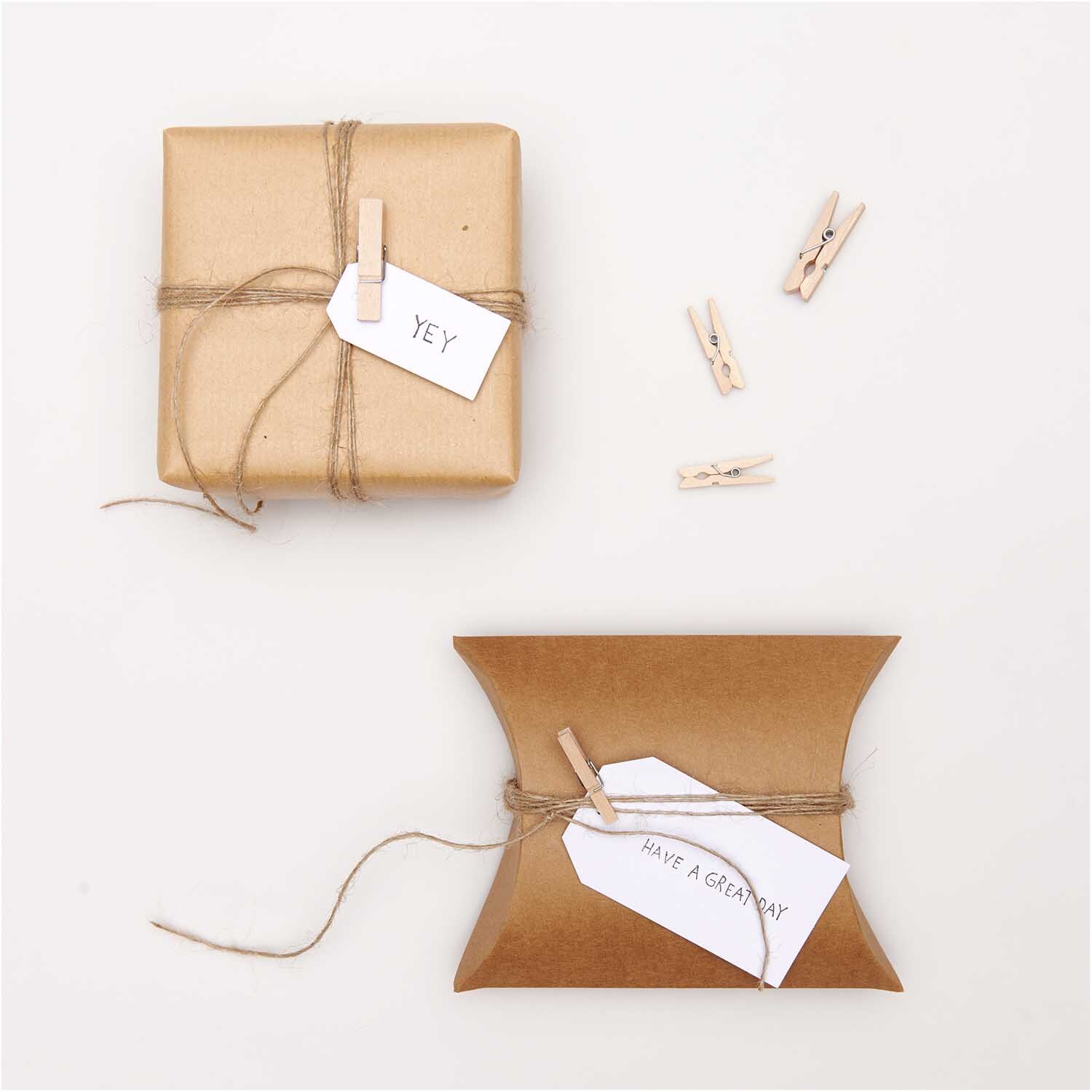 Holzklammern natur 3cm 24 Stück von Rico Design neben zwei verpackten Geschenken mit Etiketten.
