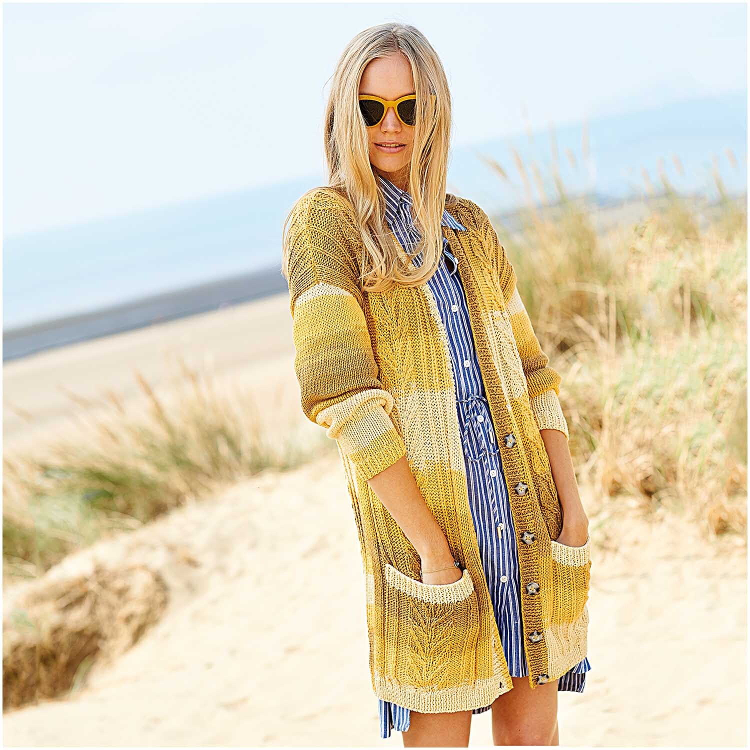 Fashion Colour Spin: Frau am Strand in gestreiftem, gelbem Rico Design Strickmantel, 100g 200m.