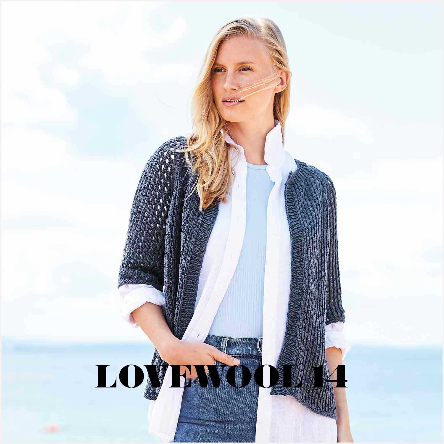 Essentials Organic Cotton aran: Frau am Strand in nachtblauem Strickcardigan von Rico Design, über weißem Hemd und hellblauem Top.