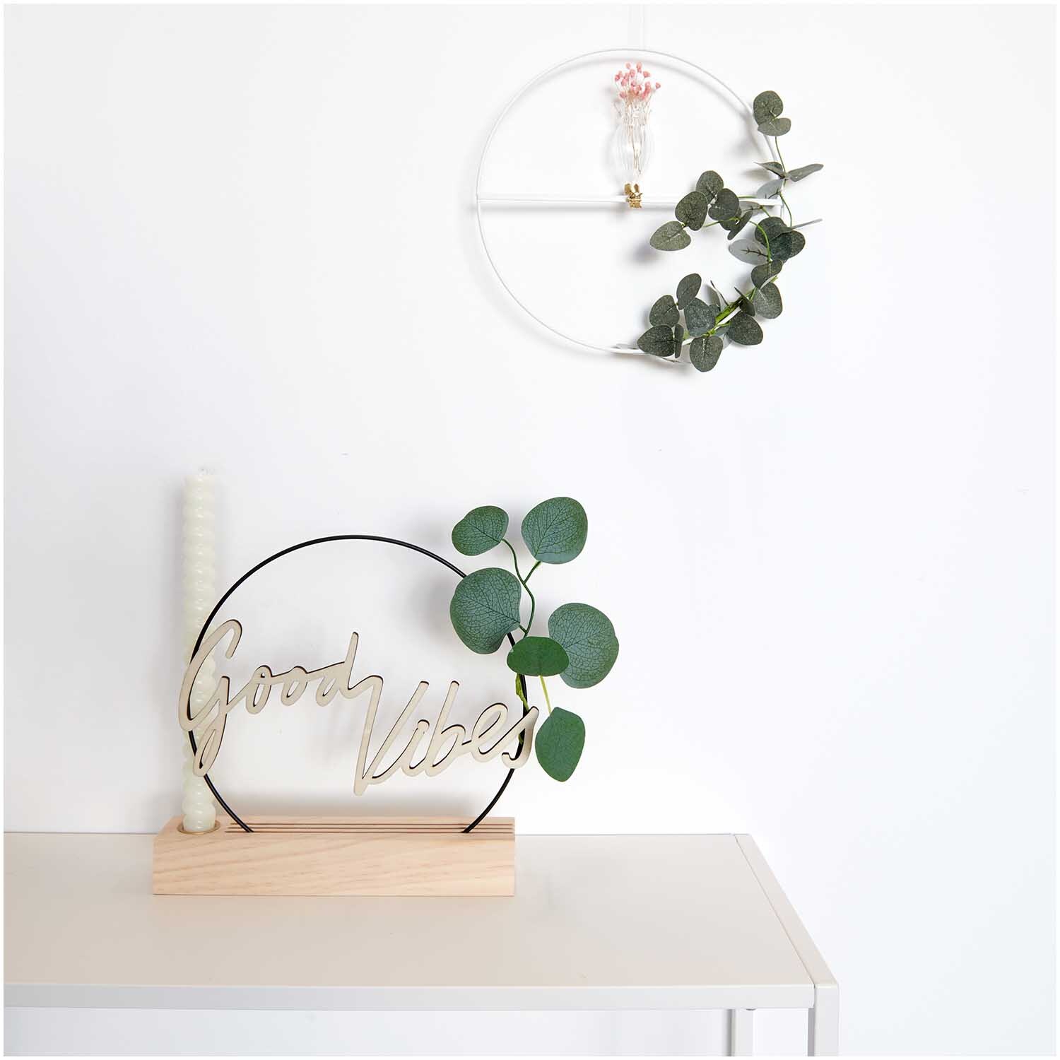 Metallring mit Querstrebe Ø25cm von Rico Design in Gold, dekoriert mit grünen Blättern und einer Kerze auf einem Tisch.