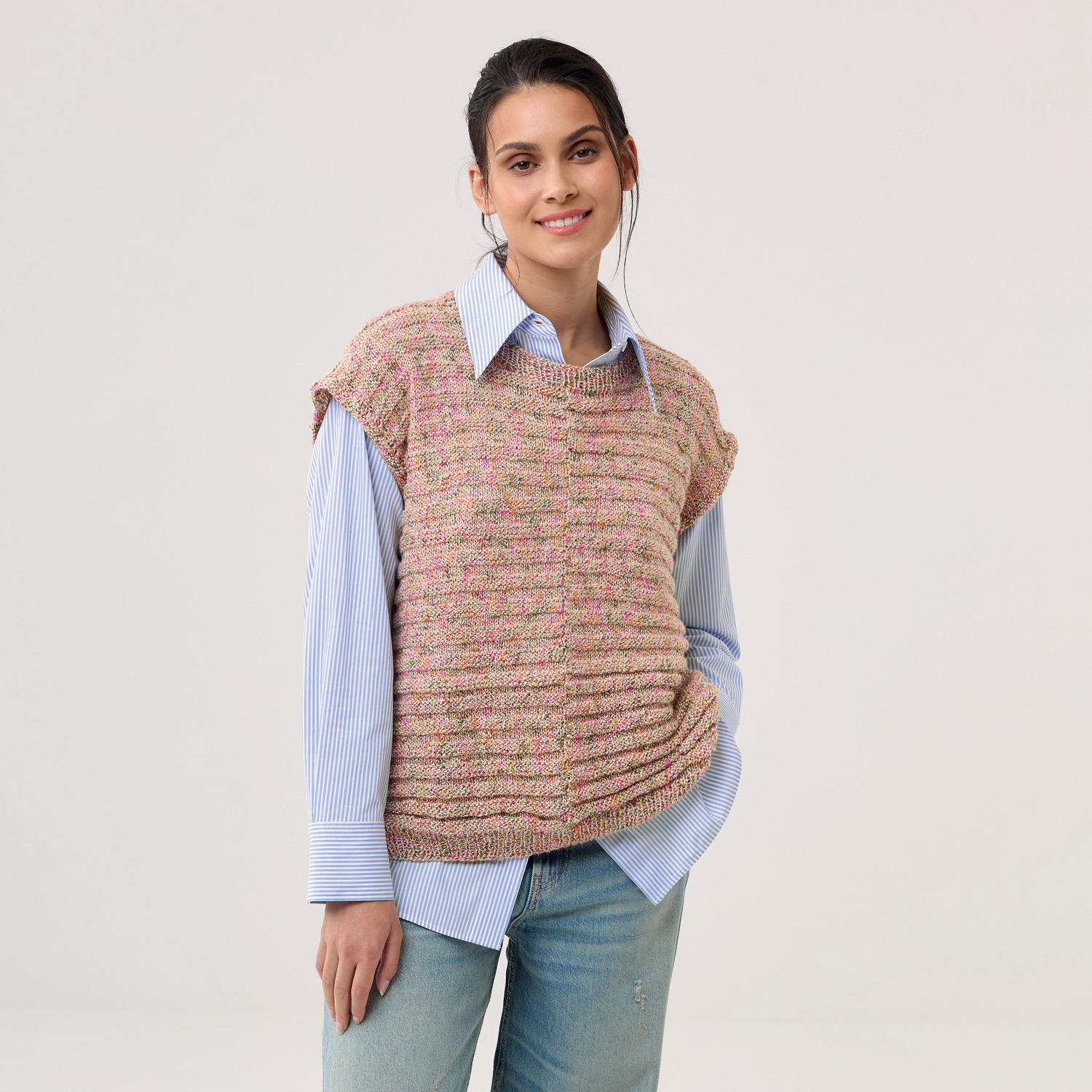 Strickset Shirt Modell 16: Frau trägt ein gestricktes Oberteil in Pastelltönen über einem blauen Hemd.