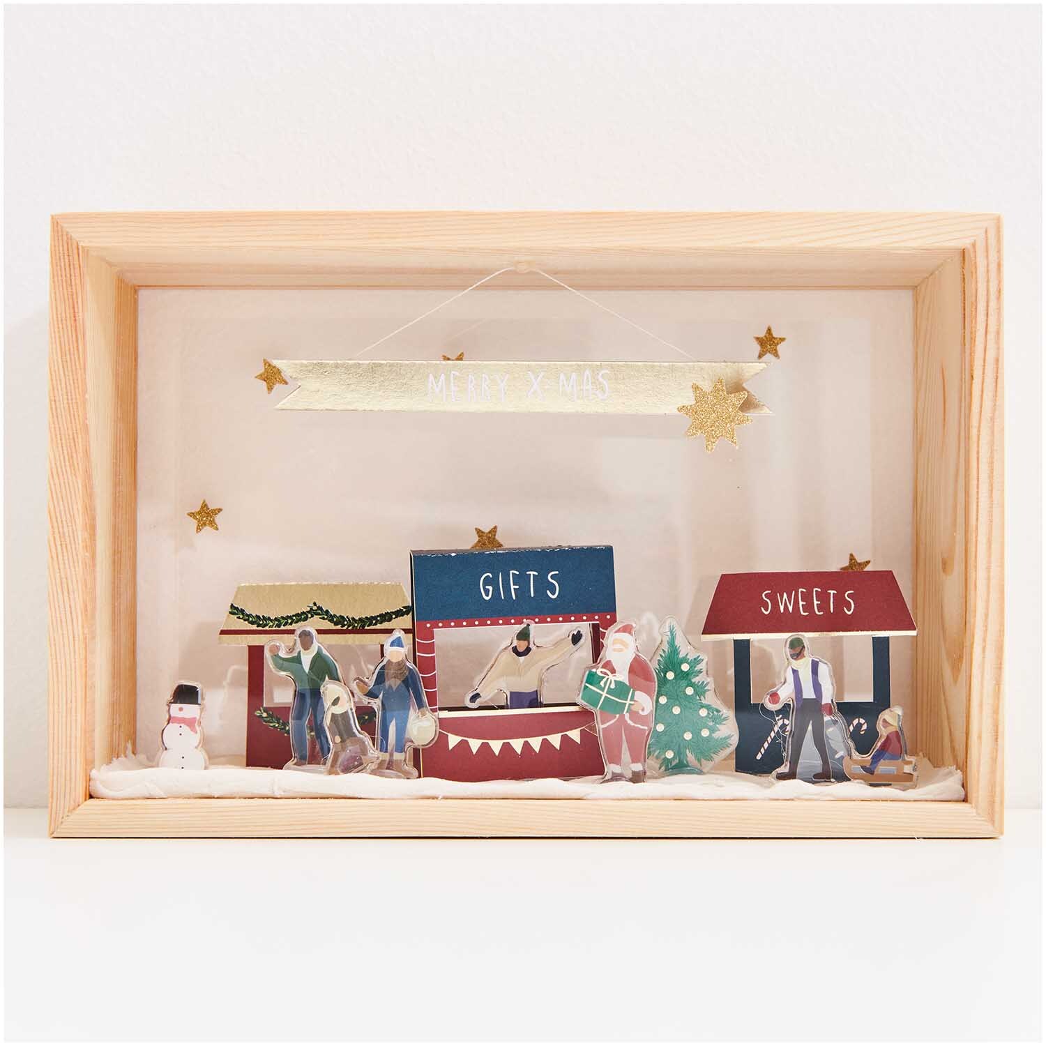 Figurico Modelliermasse 28g: Weihnachtsszene mit Marktständen, Figuren und Dekorationen in einem Holzrahmen. Ideal für kreative Bastelprojekte.
