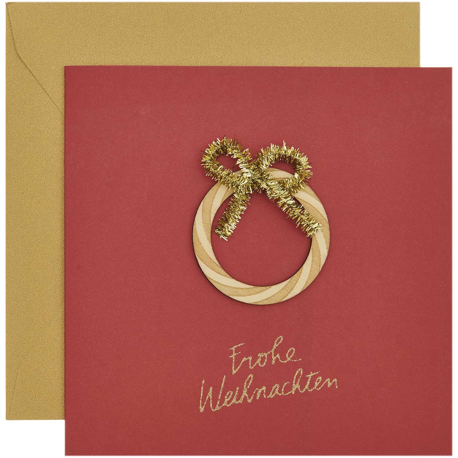 Paper Poetry Grußkarte mit goldener Schleife und Schriftzug "Frohe Weihnachten" auf rotem Hintergrund.