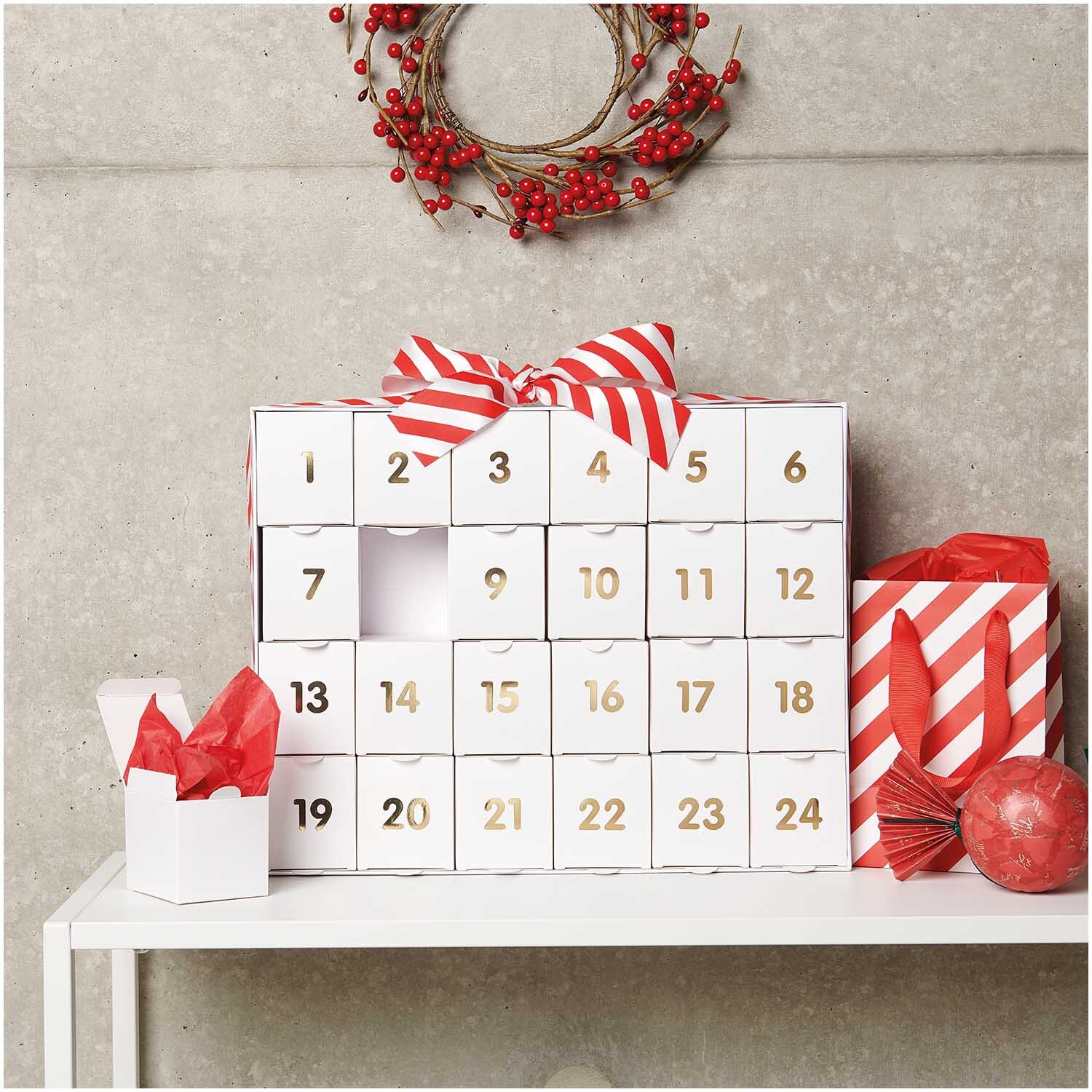 Adventskalender zum Befüllen in Weiß-Gold von Rico Design, dekoriert mit roten Akzenten und Schleife.