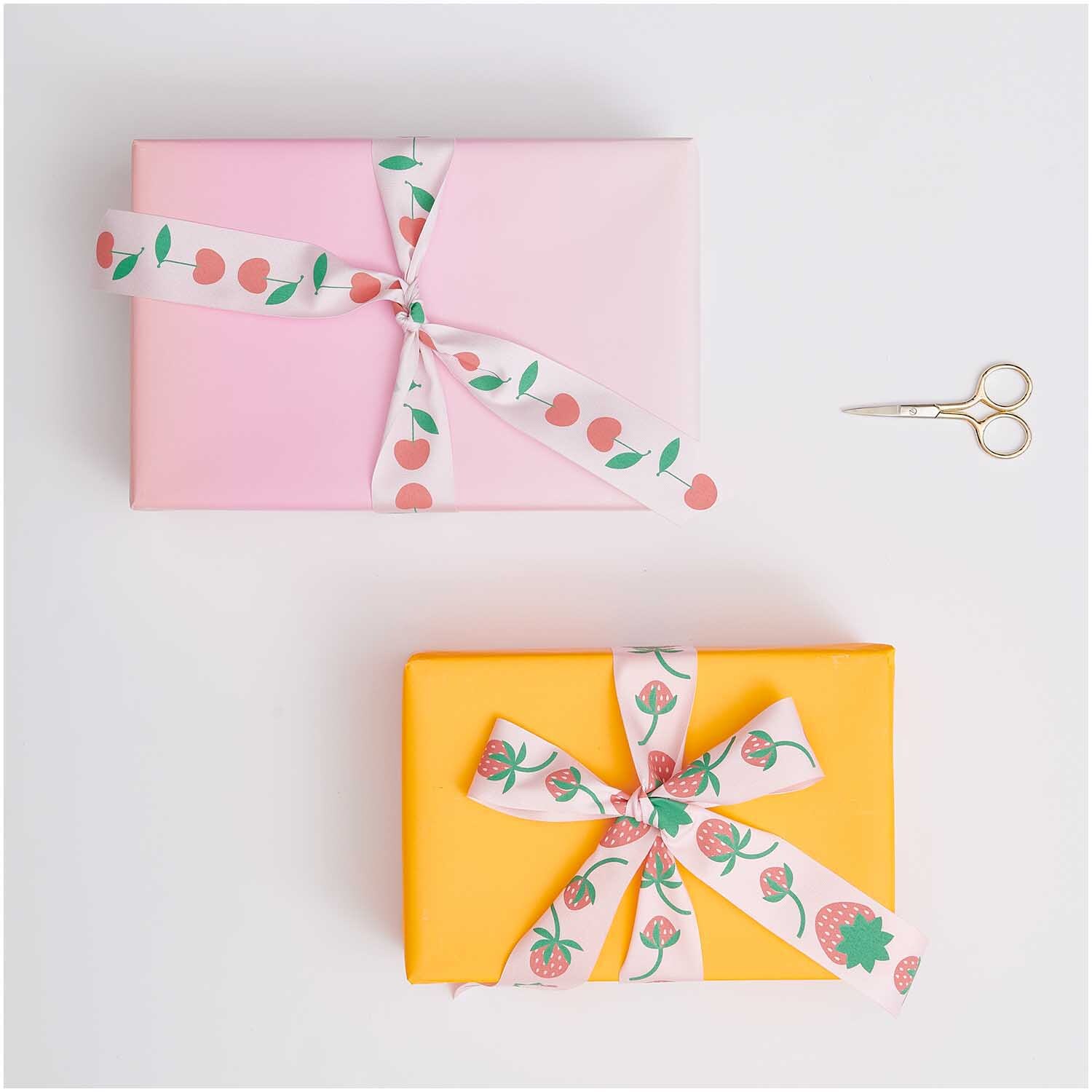 Paper Poetry Taftband Erdbeeren verziert zwei Geschenke in Rosa und Gelb, dekoriert mit Erdbeermotiven.
