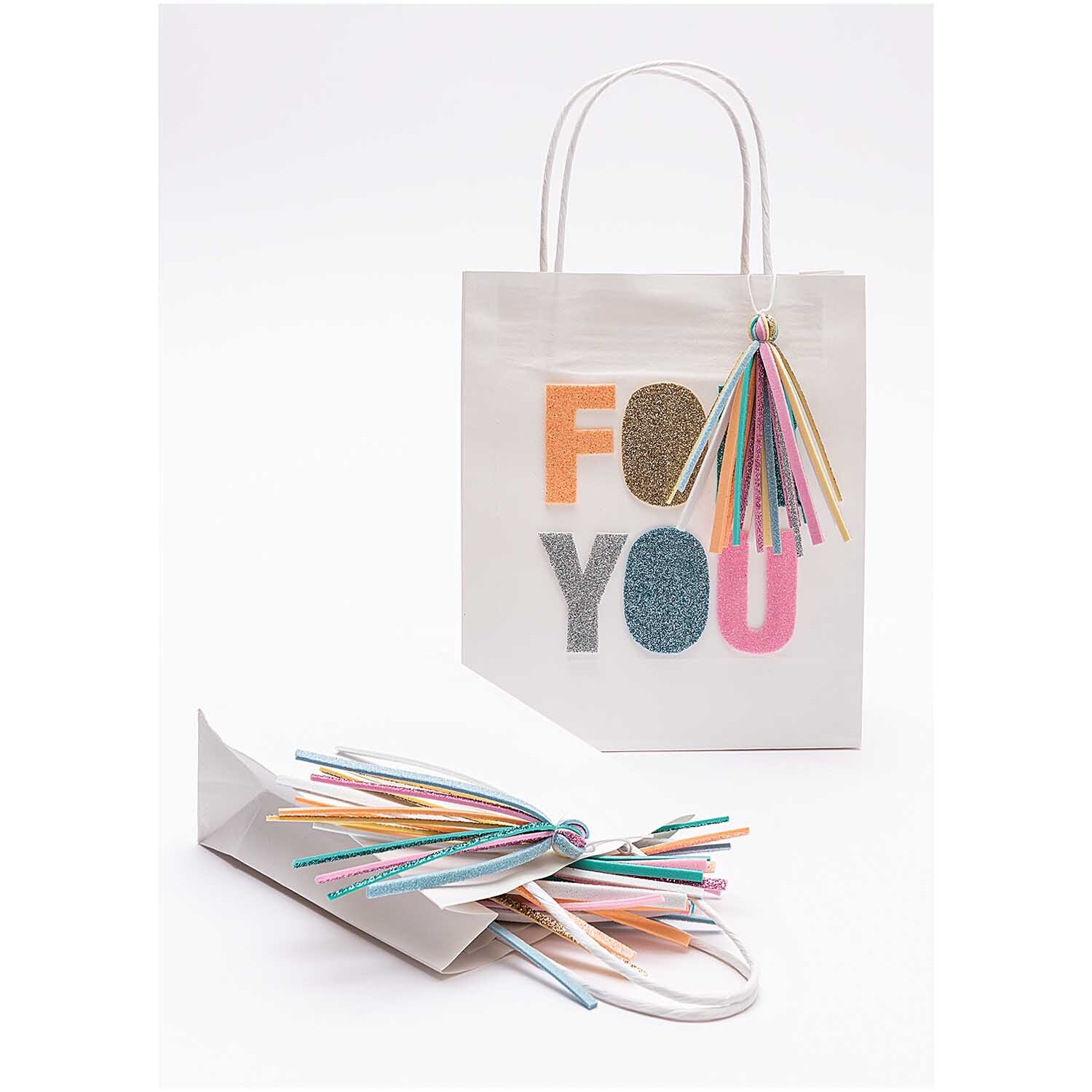 Moosgummimix 2mm 20x30cm 10 Farben: Weiße Geschenktüte mit buntem Schriftzug und Fransen.