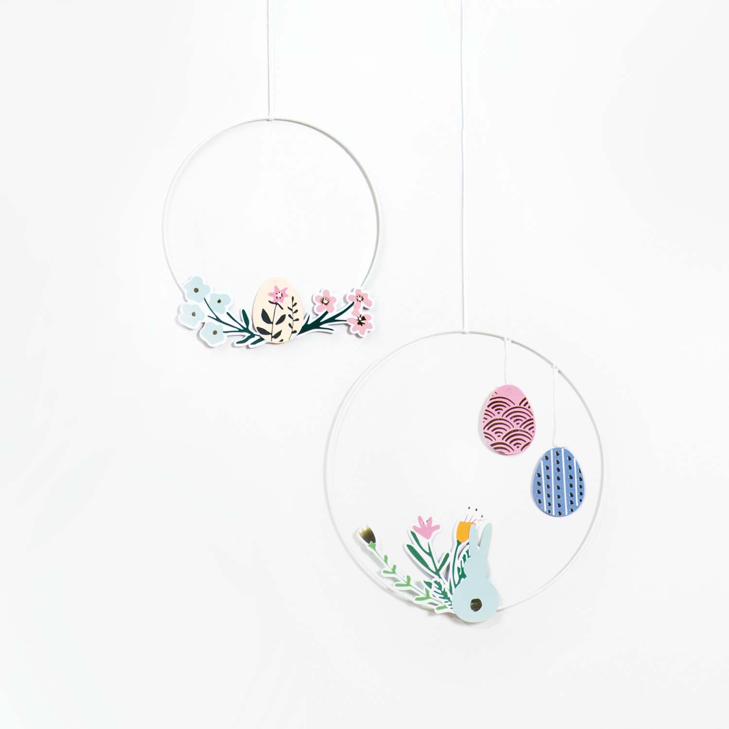 Bastelanleitung Wanddeko für Ostern: Zwei hängende Ringe mit bunten Ostereiern und Blumenmotiven.