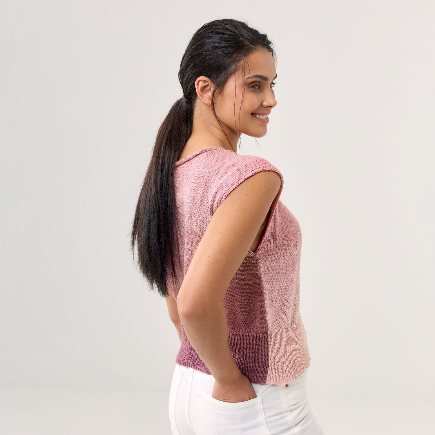Strickset Shirt Modell 11: Frau trägt ein ärmelloses, mehrfarbiges Strickshirt in Rosa- und Violetttönen.