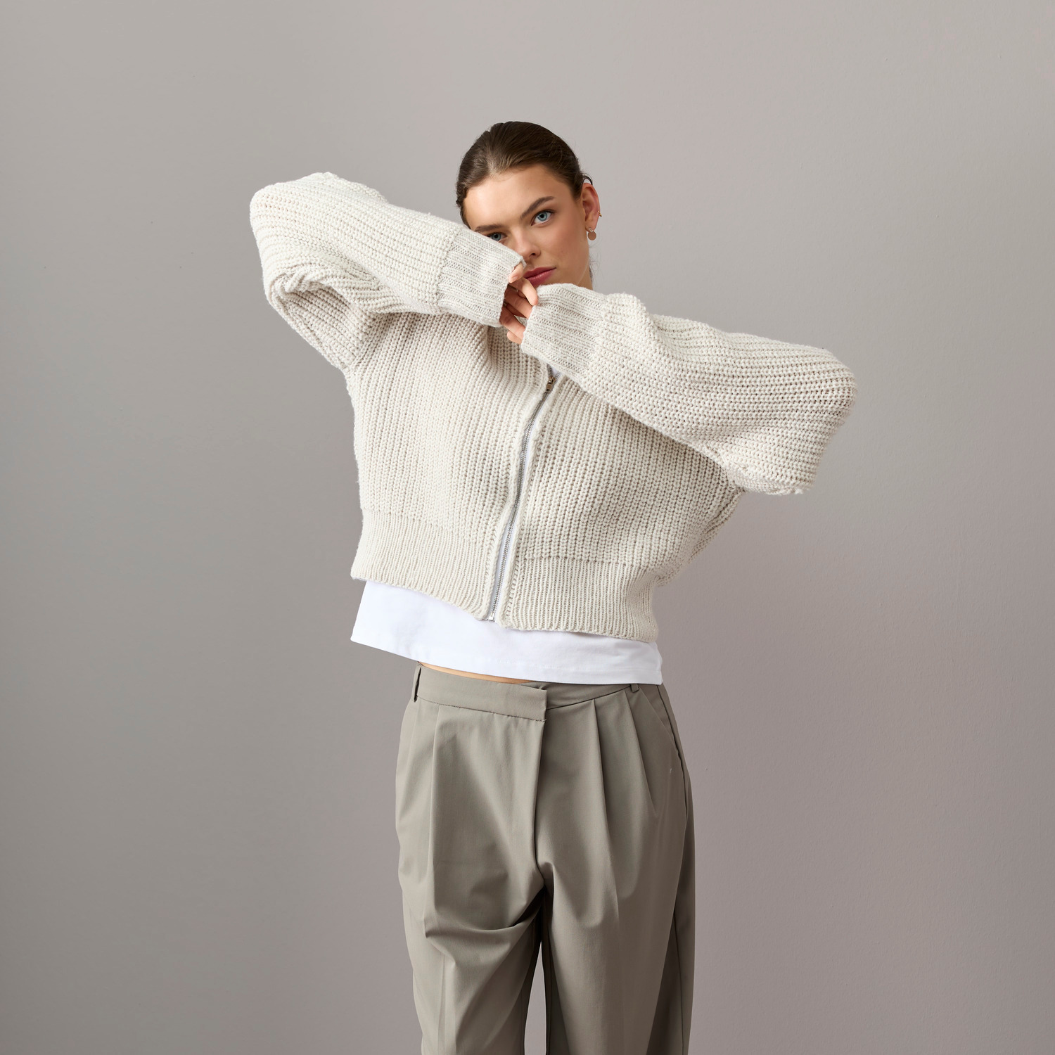 Vegan Cashmere Special: Frau trägt cremefarbenen Strickpullover von Rico Design, kombiniert mit grauer Hose.