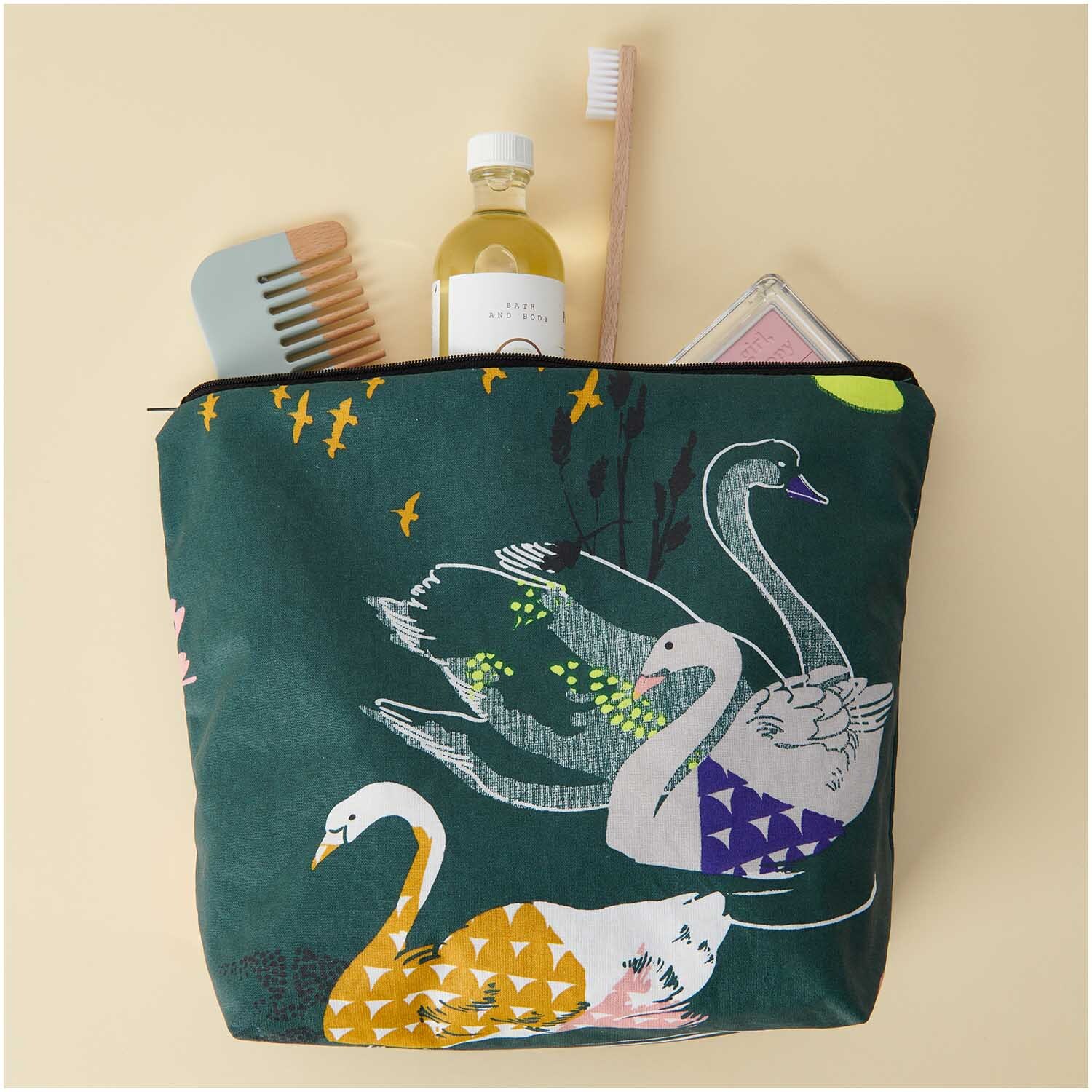 Kosmetiktasche Okina Hana dunkelgrün mit Schwanenmotiv, gefüllt mit Pflegeprodukten und Accessoires. Ideal für stilvolle Aufbewahrung.