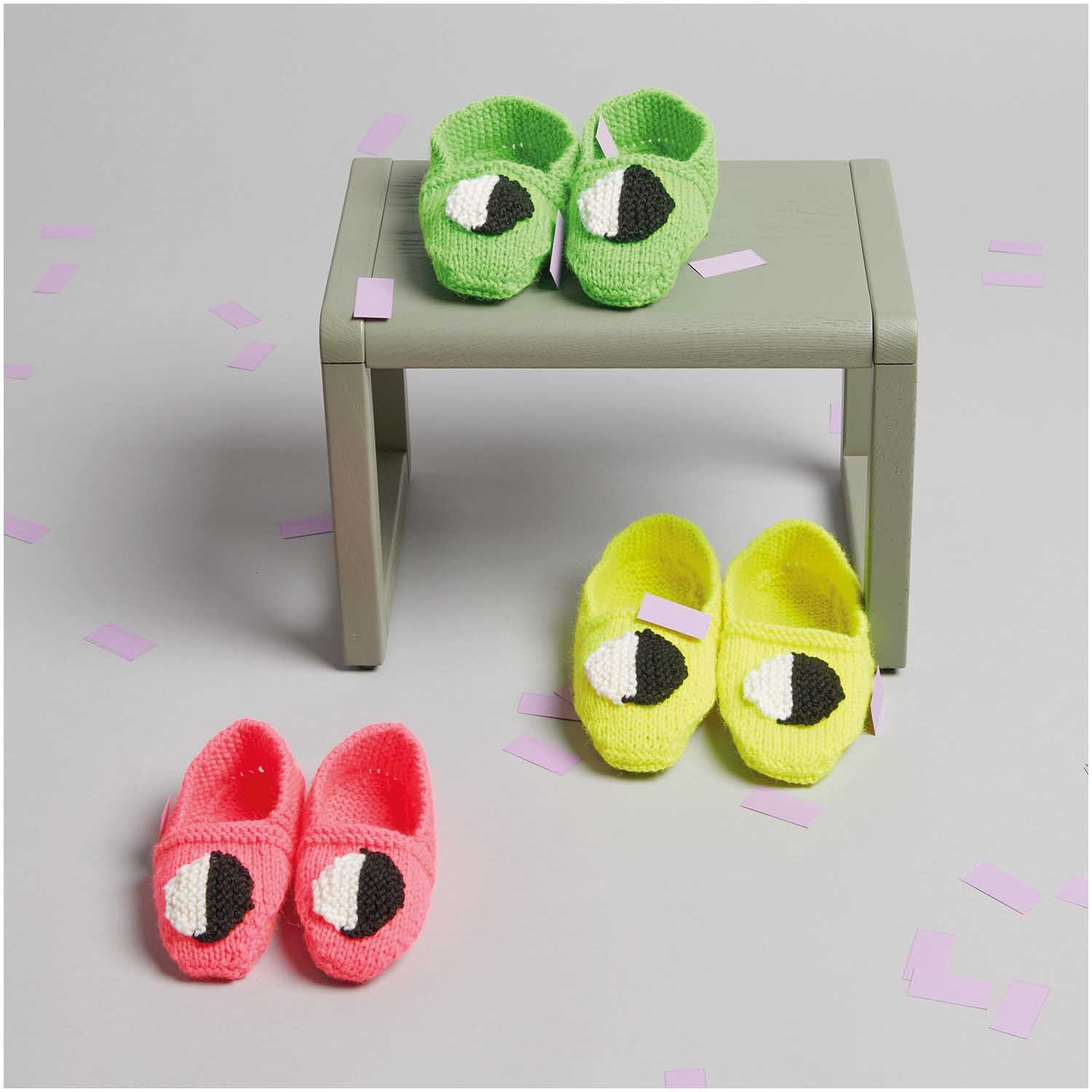 Socks Neon 4-fädig: Handgestrickte Babyschuhe in leuchtenden Farben auf grauem Tisch, ideal für kreative Strickprojekte.