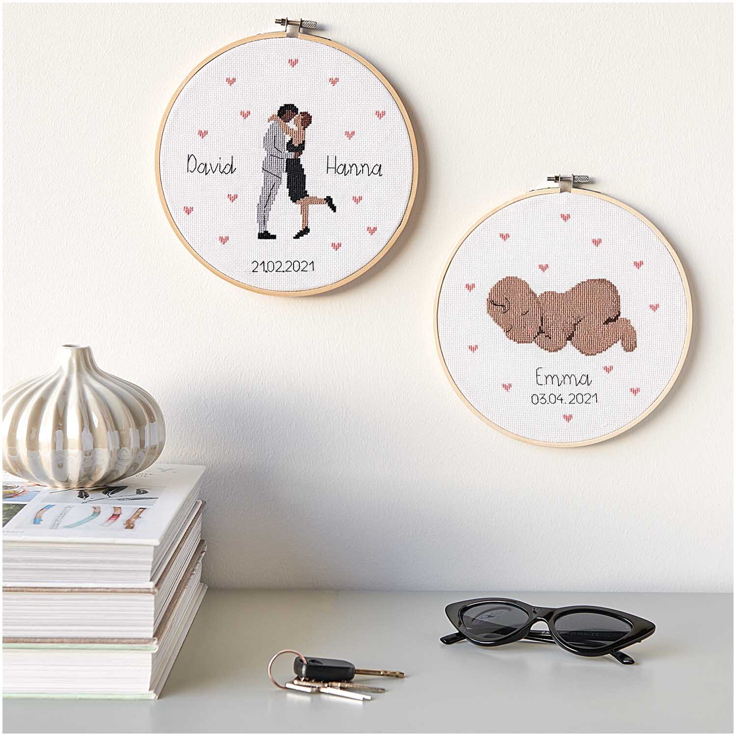 Figurico Stickpackung Lovebirds 20cm zeigt zwei bestickte Rahmen mit Paar und Baby, umgeben von Herzen. Ideal für personalisierte Geschenke.