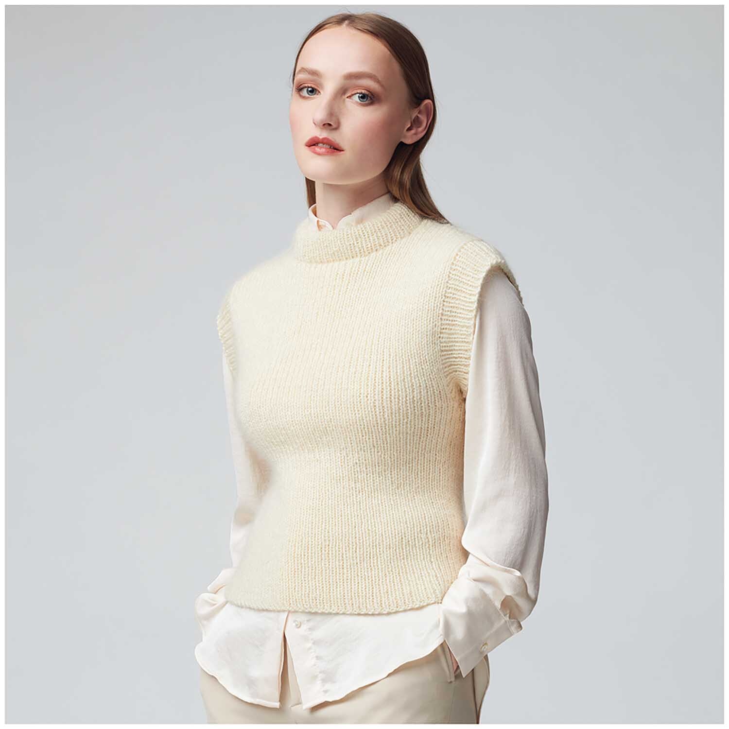 Essentials Super Kid Mohair Loves Silk: Frau trägt cremefarbenen Strickpullover über weißer Bluse, elegant und stilvoll.