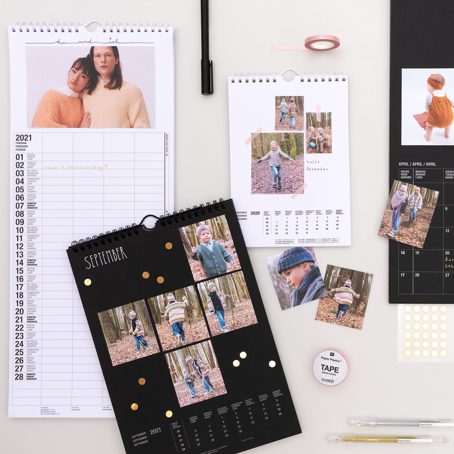 Bastelanleitung Jahreskalender zum Selbstgestalten: Verschiedene Kalenderlayouts mit Fotos und Bastelmaterialien auf einem Tisch arrangiert.
