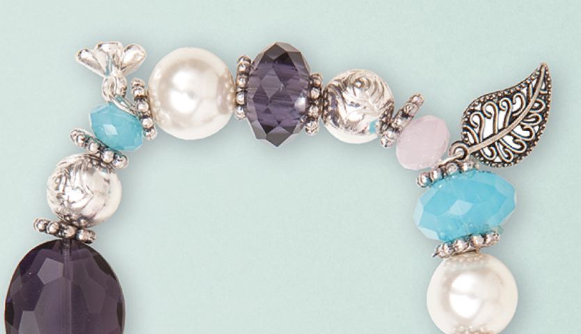 Anleitung Perlenset Fashion Armband basteln: Elegantes Armband mit bunten Perlen und filigranem Blattanhänger auf hellem Hintergrund.