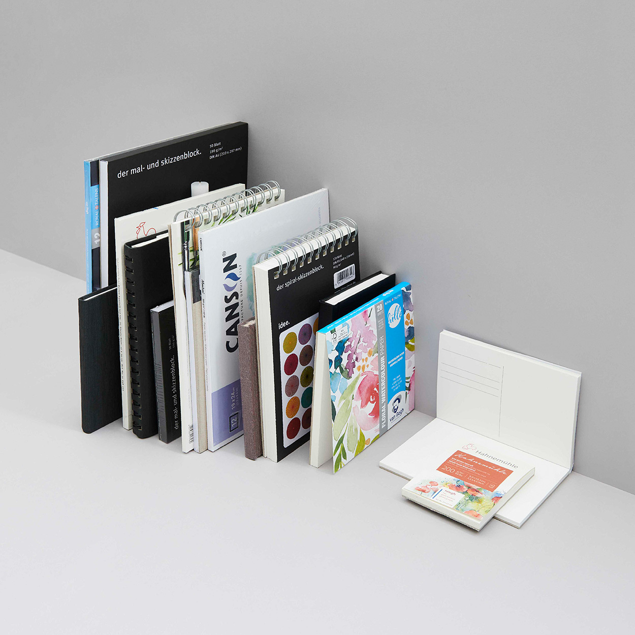 Mehrere Skizzen- und Malbücher aneinandergereiht. Fotosetting graue Ecke.